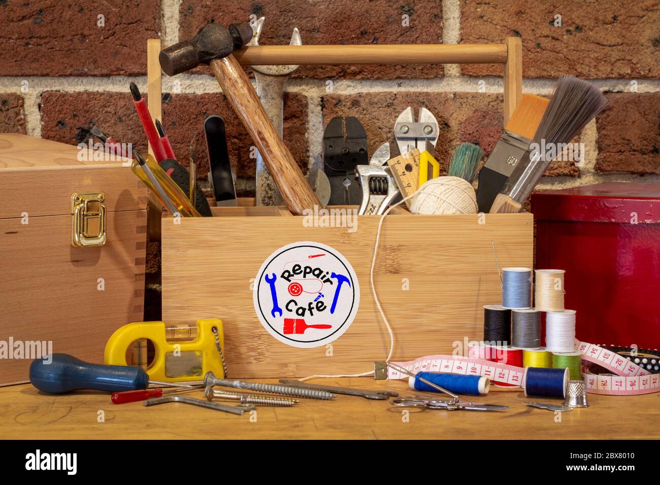 Autocollant du logo du café de réparation sur la boîte à outils entouré d'outils de réparation sur le banc dans le café utilisé comme centre de réparation, activisme de consommateur pour réparer les articles ménagers Banque D'Images