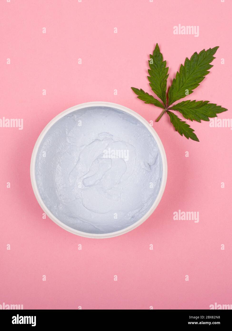 soins de la peau avec de la marijuana médicale. feuille de cannabis vert et crème sur fond rose. Banque D'Images