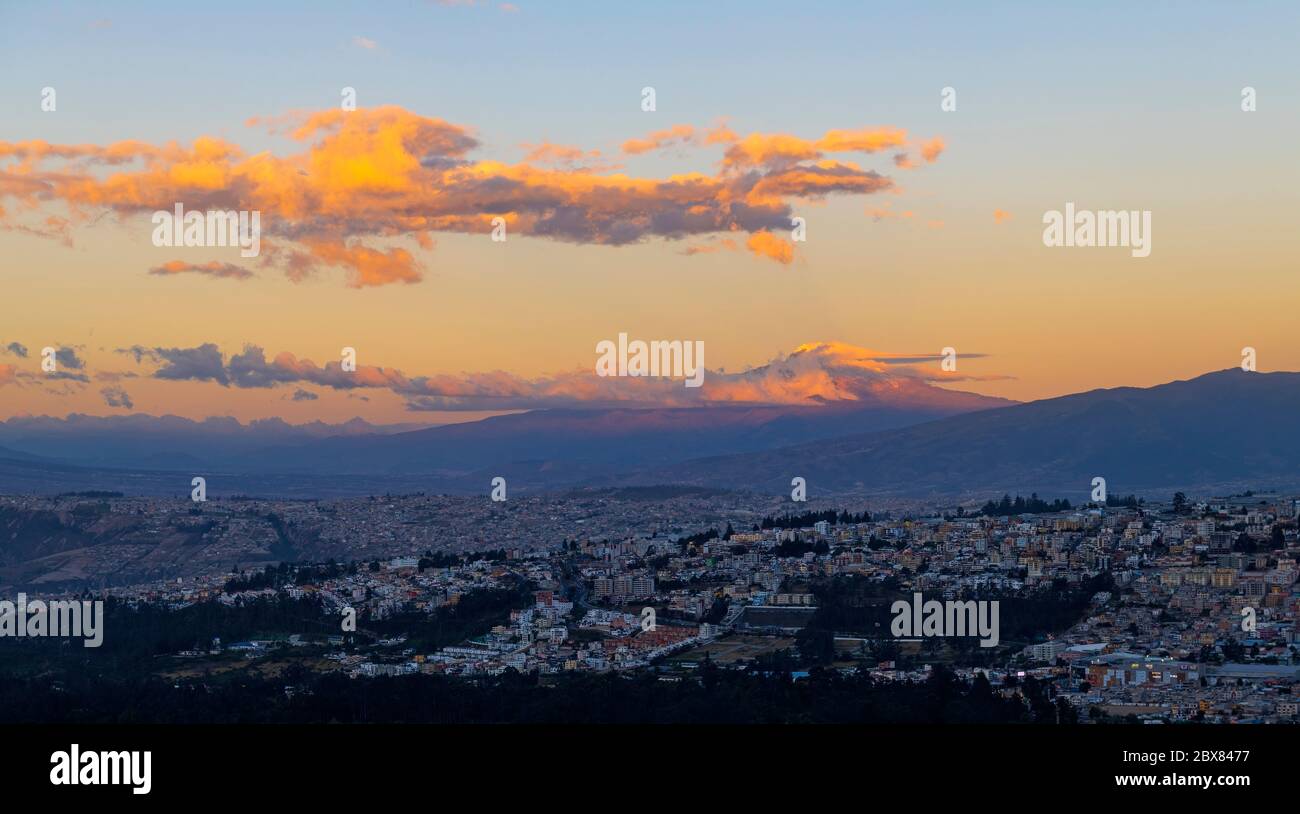 Coucher de soleil à Quito avec ses gratte-ciel et le volcan lumineux Cayambe, Equateur. Banque D'Images