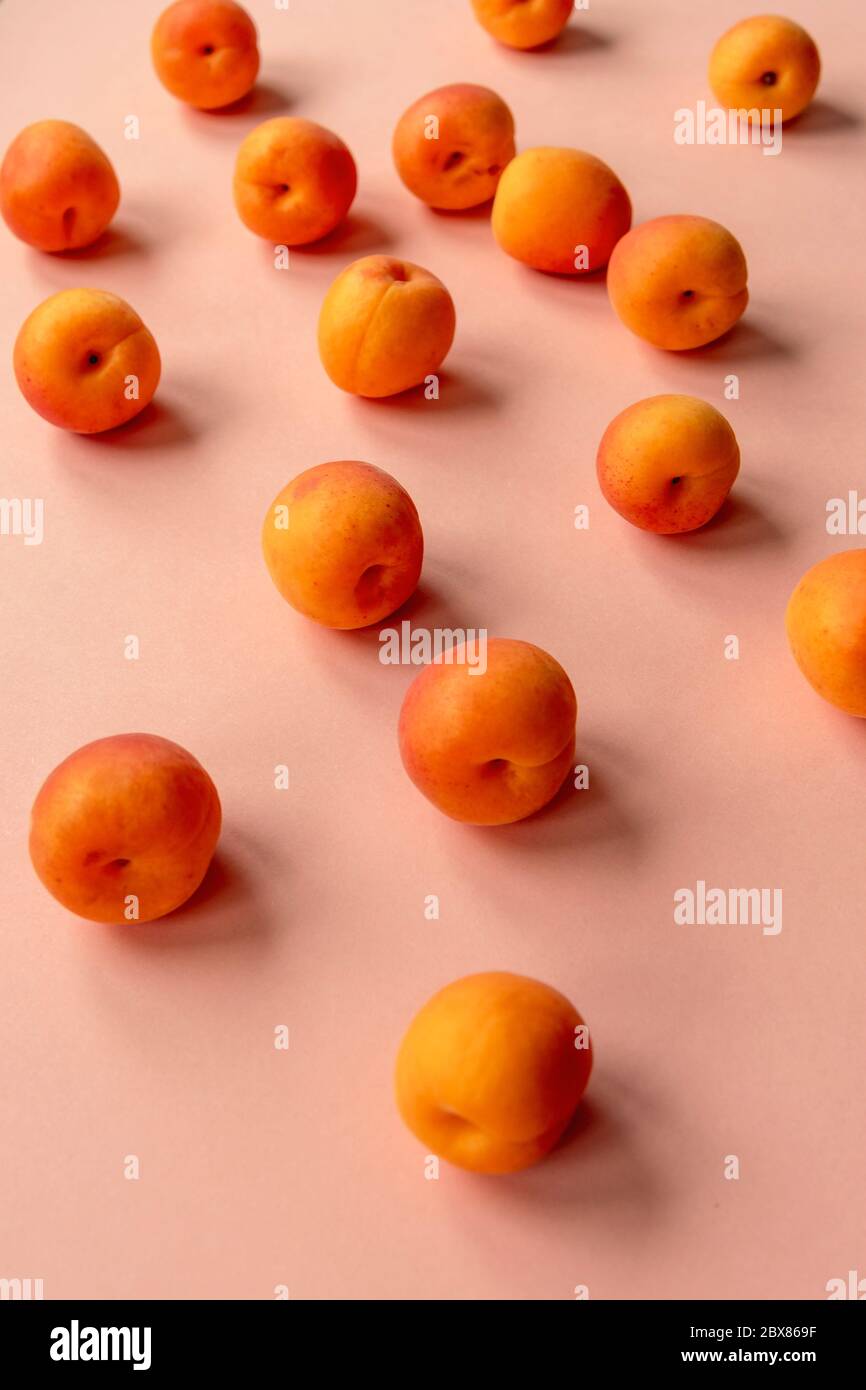 Abricots orange dispersés sur une table rose. Healthz Food concept, gros plan Banque D'Images