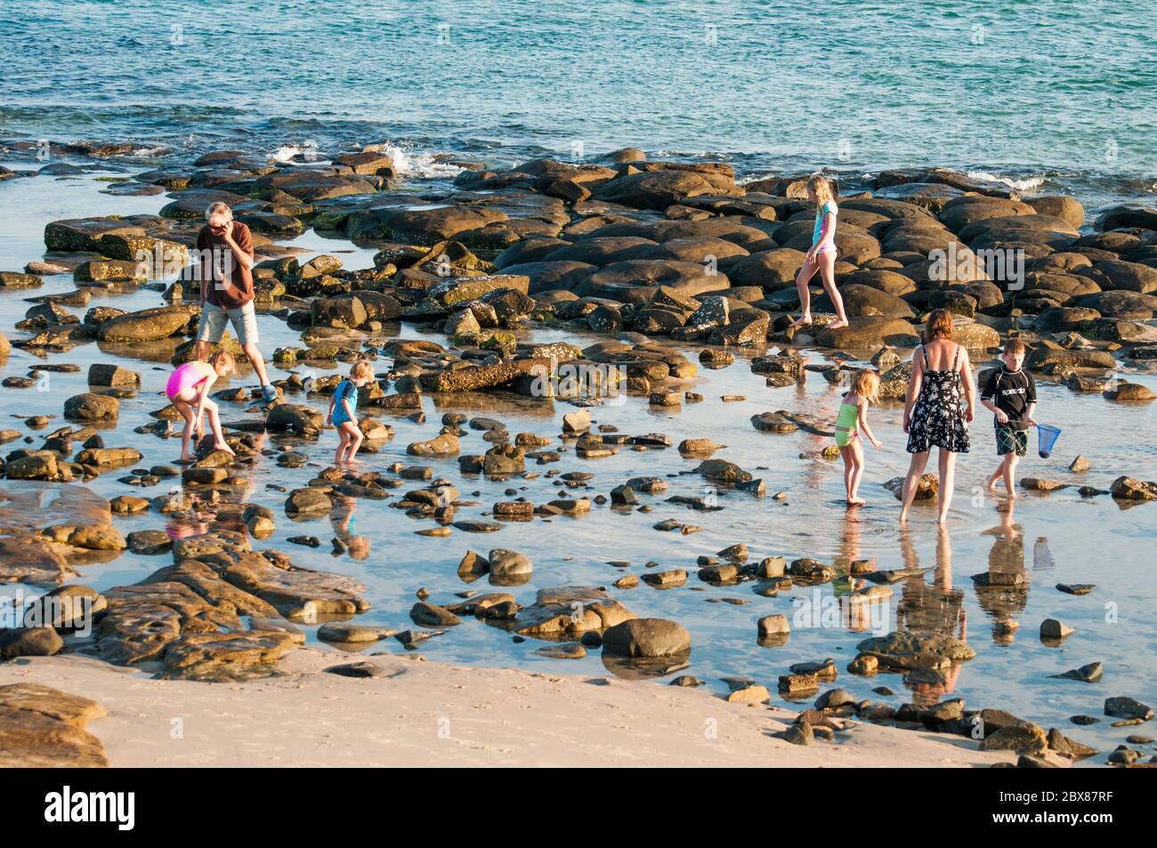 Familles qui pataugent dans les bassins de roche de Bulcock Beach, Caloundra, Sunshine Coast, Queensland, Australie Banque D'Images