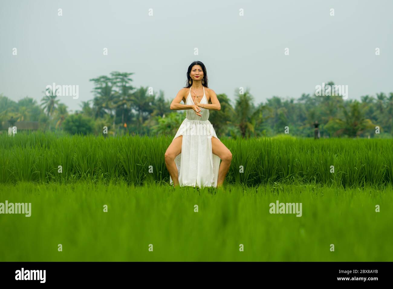 Corps et esprit connexion avec la nature - heureuse et belle femme coréenne asiatique faisant yoga et méditation exercice à l'extérieur dans le champ idyllique de riz vert Banque D'Images