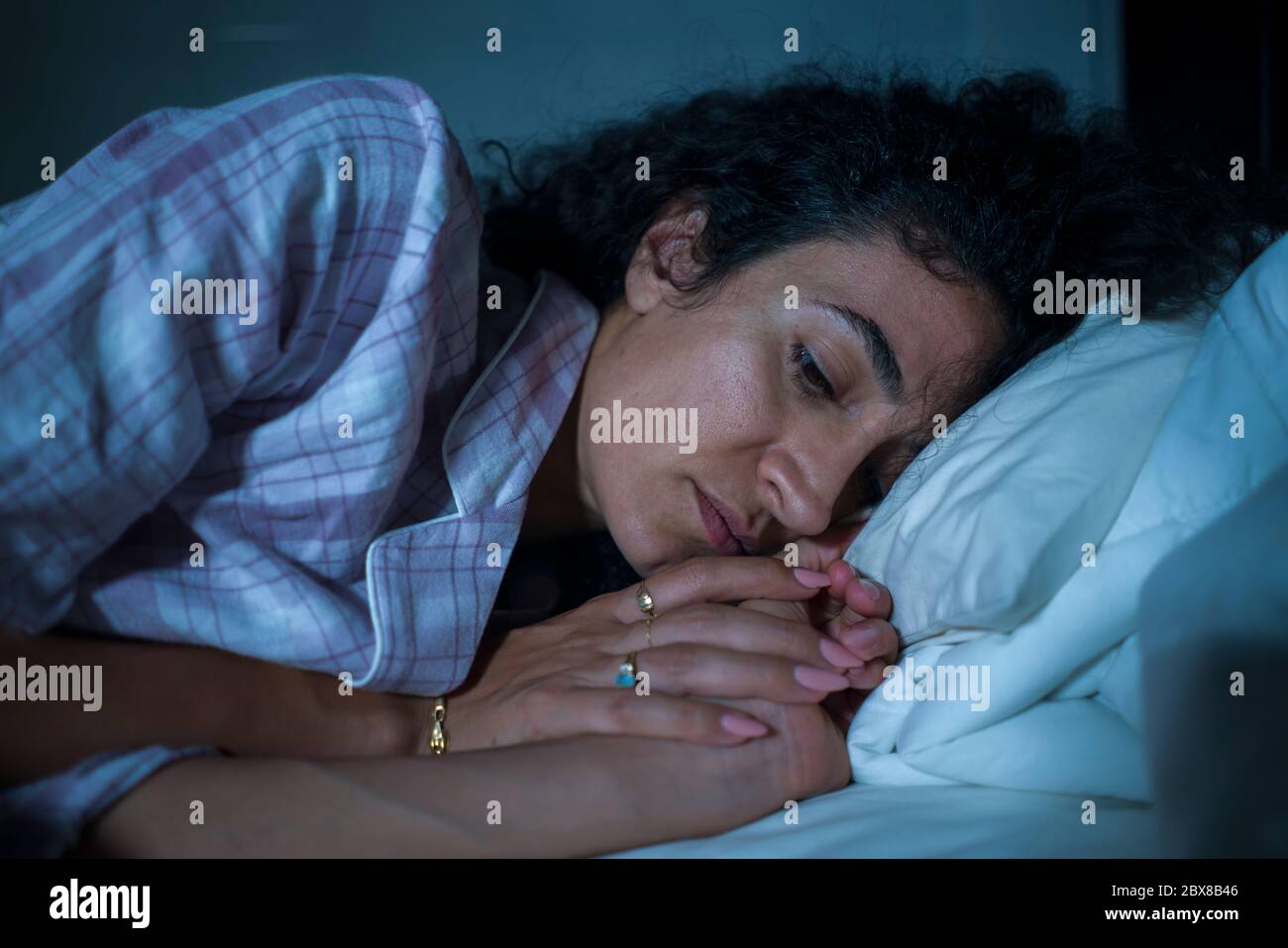 portrait nocturne dramatique de la jeune femme hispanique triste et dépressive avec des cheveux mauriquement sans sommeil dans le lit éveillé et sentiment réfléchi de suff inquiet Banque D'Images