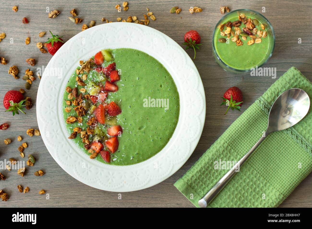 Bol à smoothie vert avec banane, fraise, épinards, chou vert, kiwi, lait de coco garni d'avoine maison, granola aux noix et graines, flocons de noix de coco, chia Banque D'Images