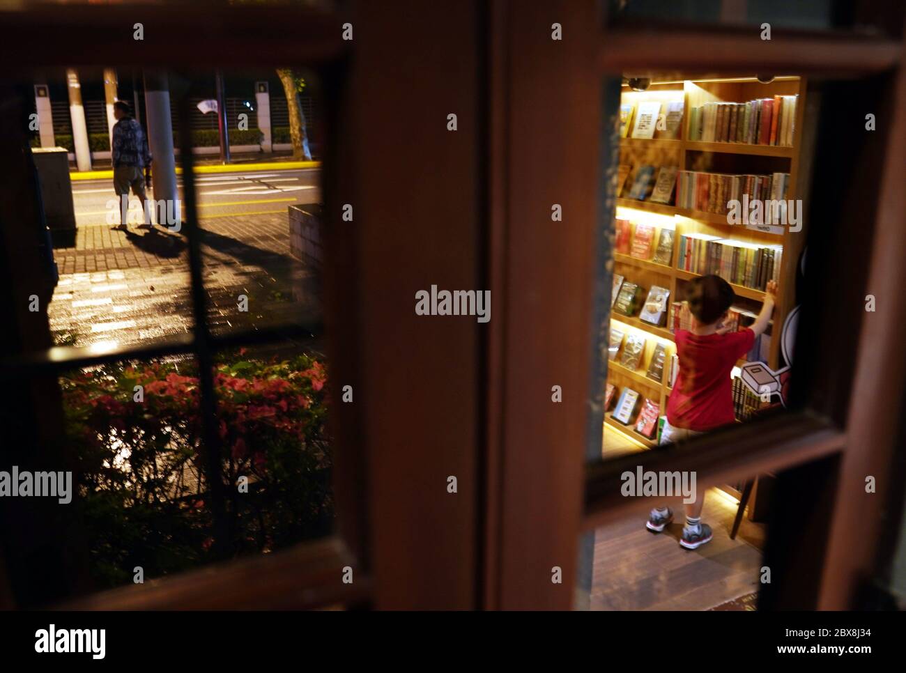 Shanghai, Chine. 5 juin 2020. Un lecteur et un piéton sont vus dans et à l'extérieur de l'un des livres sinan à Shanghai, en Chine orientale, le 5 juin 2020. Sinan Books a commencé à fournir des « bureaux de nuit » pour les lecteurs jusqu'à 24 heures tous les vendredis et samedis soirs du 5 juin au 30 juin, qui ne peuvent être réservés que sur Internet, dans le cadre de l'activité « librairie de nuit » qui a dévoilé à Shanghai le samedi. Credit: Liu Ying/Xinhua/Alay Live News Banque D'Images