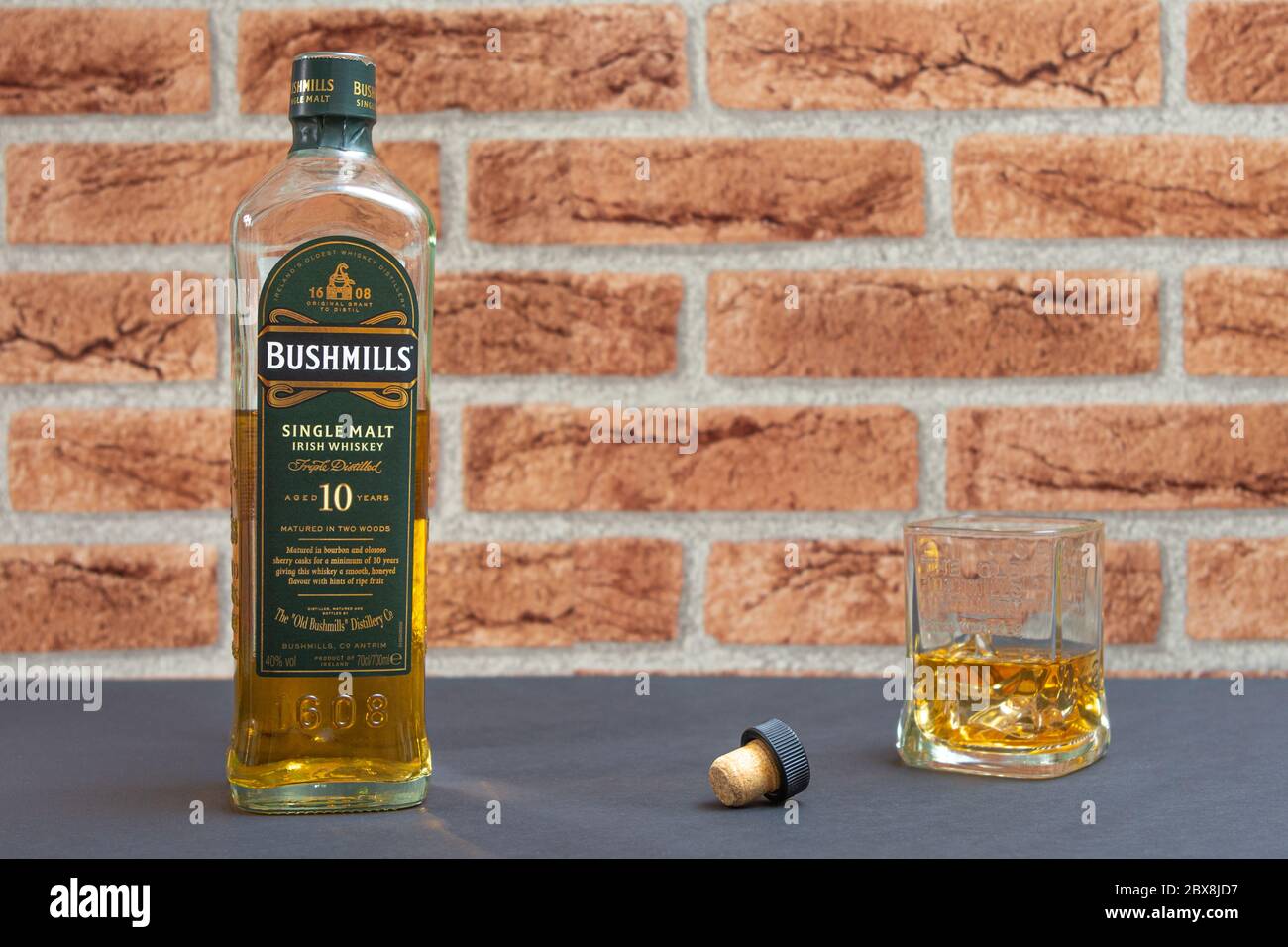 Une bouteille de whisky single malt Bushmills avec un verre sur fond de clinker Banque D'Images