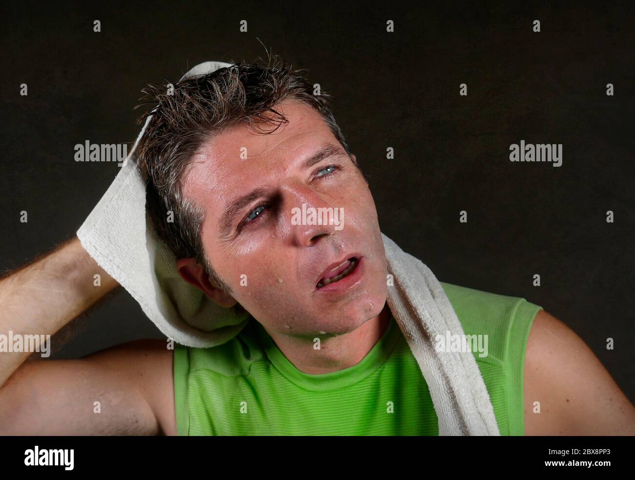 jeune homme de sport fatigué et épuisé avec une serviette sur son cou sueur et respirante après l'entraînement dur et l'entraînement de forme physique isolé sur fond sombre i Banque D'Images