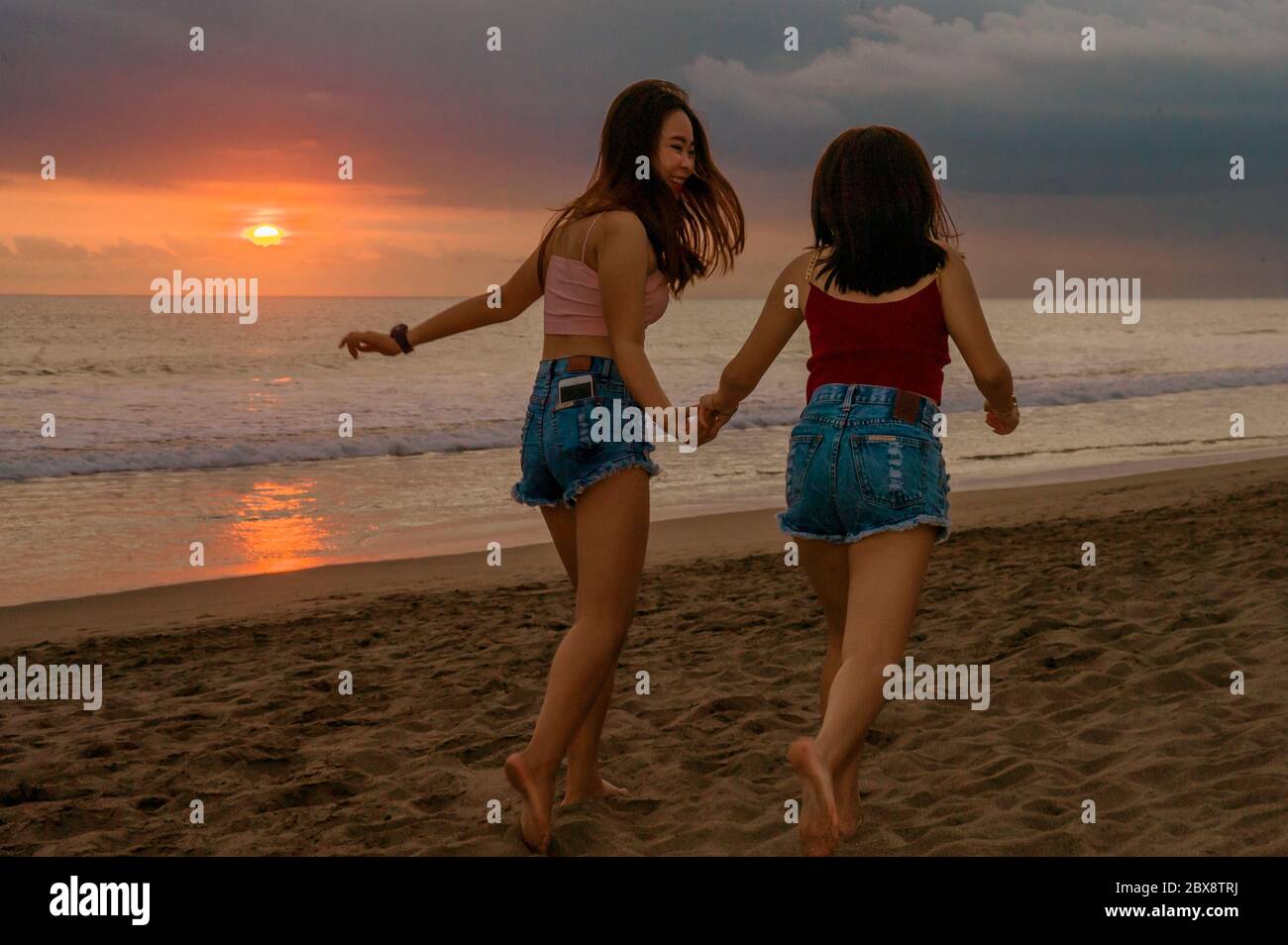 Style de vie en plein air portrait de deux jeunes sœurs ou une fille  asiatique chinoise au coucher du soleil sur la plage avec sa meilleure amie  qui s'amuse en vacances d'été