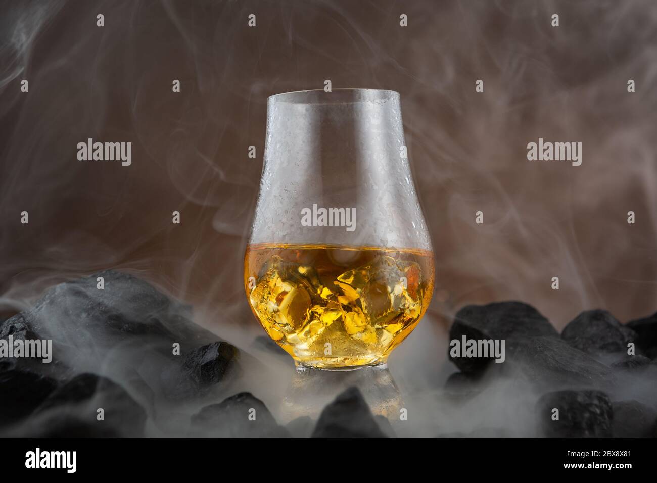 Whisky dans un verre de whisky Glencairn, assis sur le charbon, le whisky, le charbon et la fumée Banque D'Images