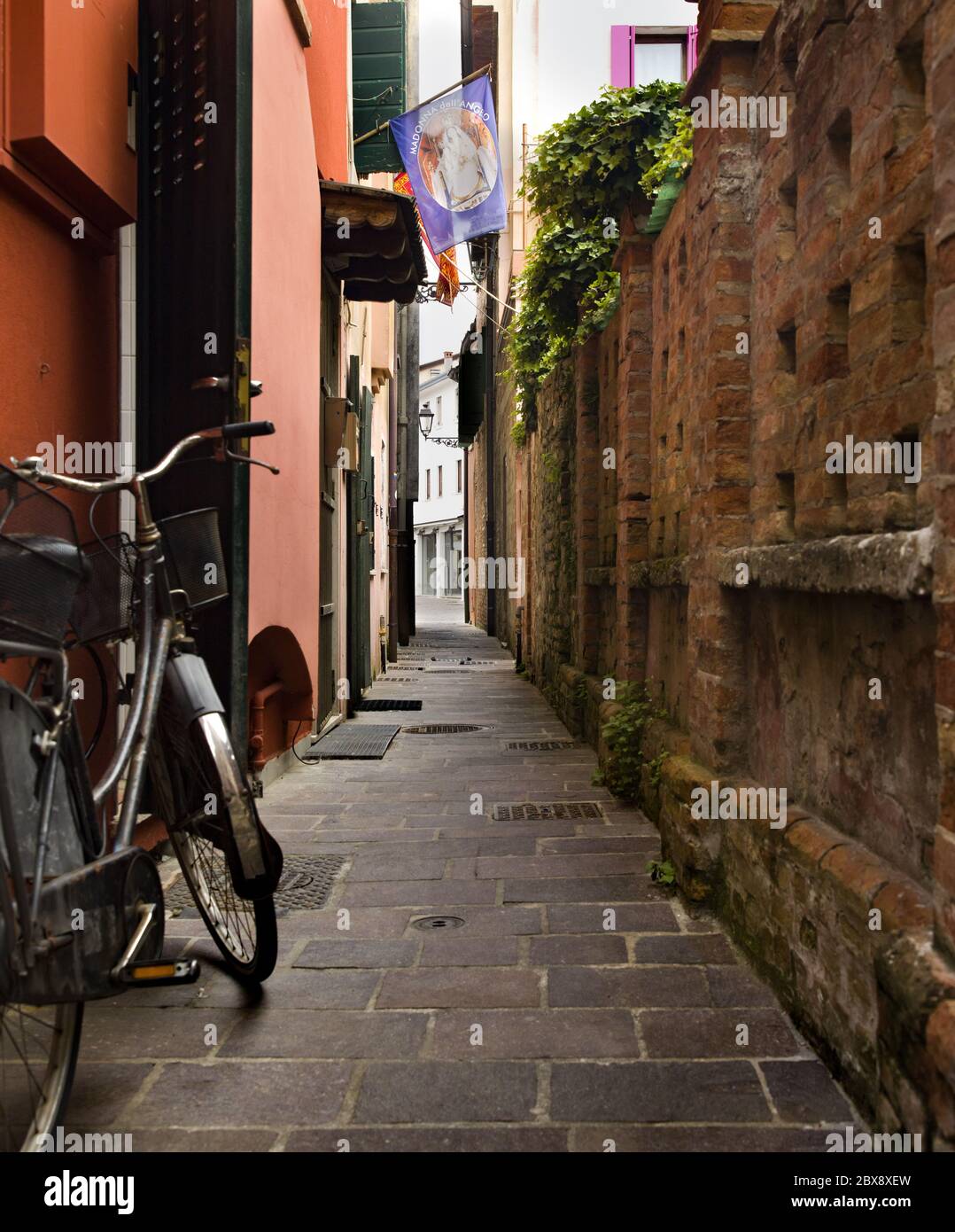 Tourisme en Vénétie et point d'intérêt parmi les ruelles étroites et les maisons maritme à Caorle port avec des vélos et des maisons colorées. Banque D'Images