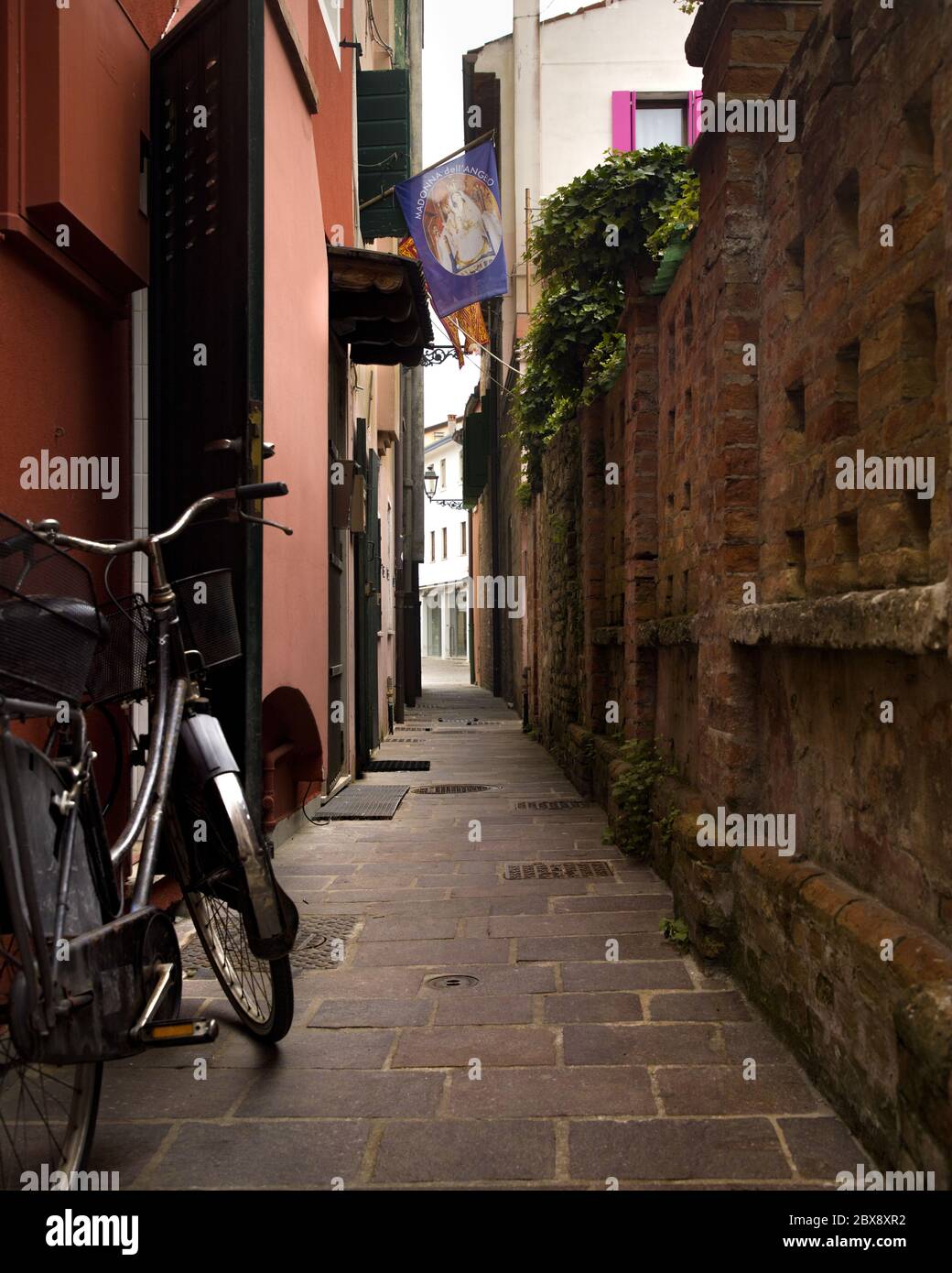 Tourisme en Vénétie et point d'intérêt parmi les ruelles étroites et les maisons maritme à Caorle port avec des vélos et des maisons colorées. Banque D'Images