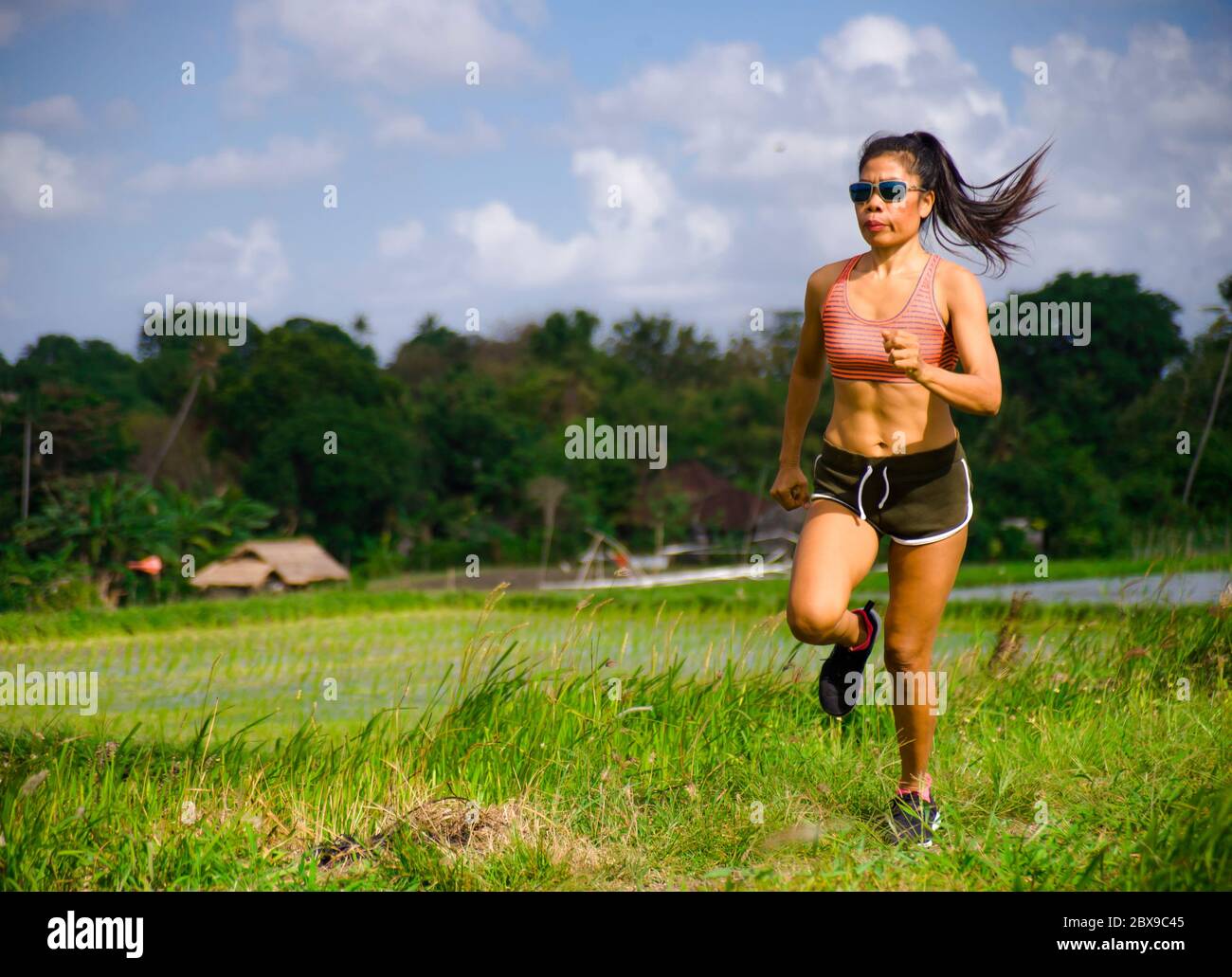 Attrayant et très en forme asiatique sport femme entraînement entraînement entraînement à la course à pied sur le terrain vert paysage arrière-plan travailler dur dans un style de vie sain et la compétition Banque D'Images
