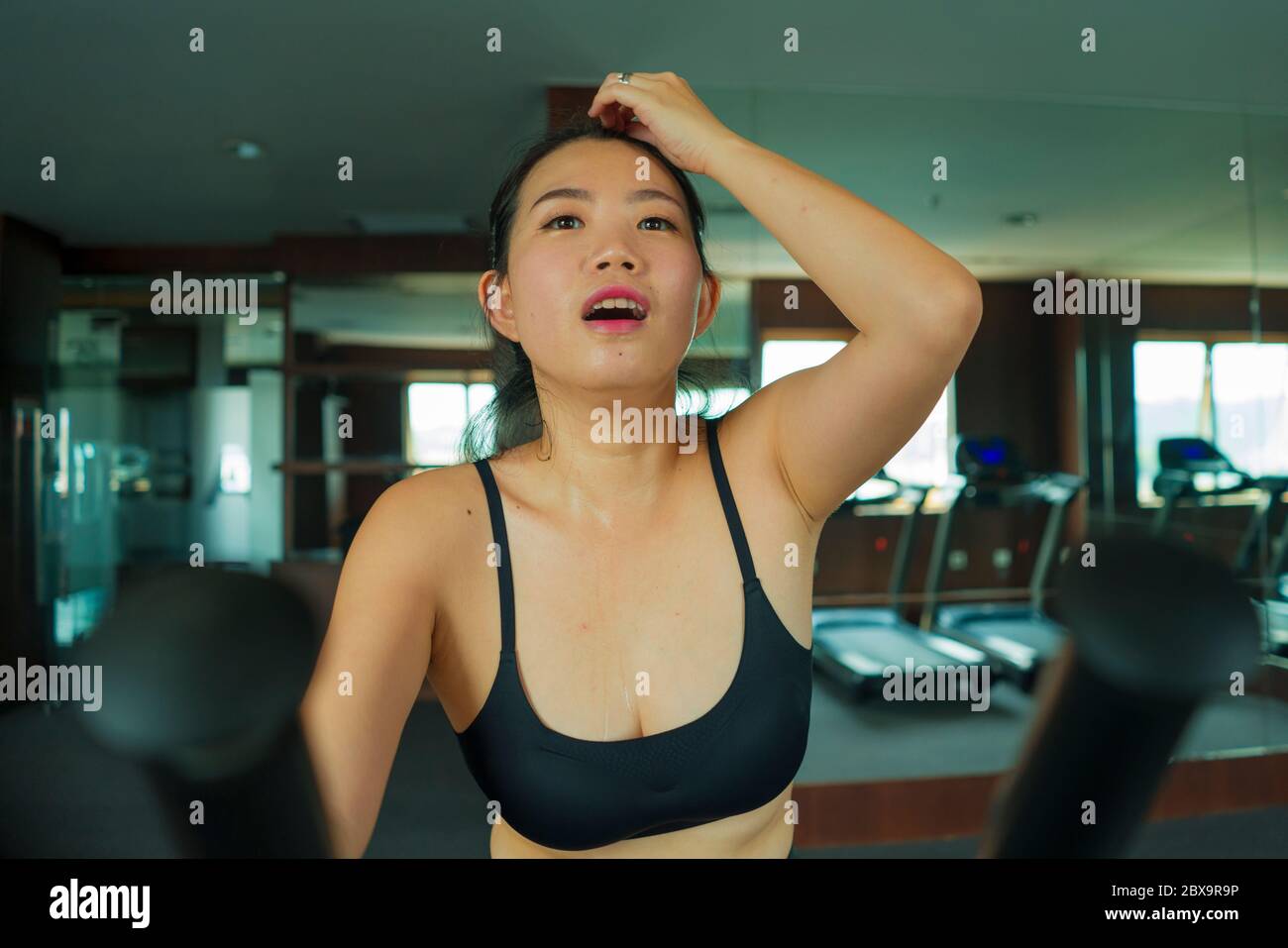 Portrait de séance de jeune femme asiatique belle et heureuse entraînement de femme coréenne à l'hôtel gym ou club de fitness travaillant dur dans cardio machine elliptique à sp Banque D'Images