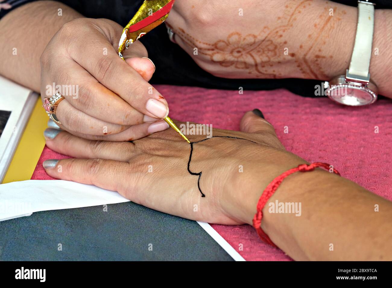 Artiste appliquant le tatouage au henné sur les mains des femmes pendant le festival de la culture orientale Banque D'Images