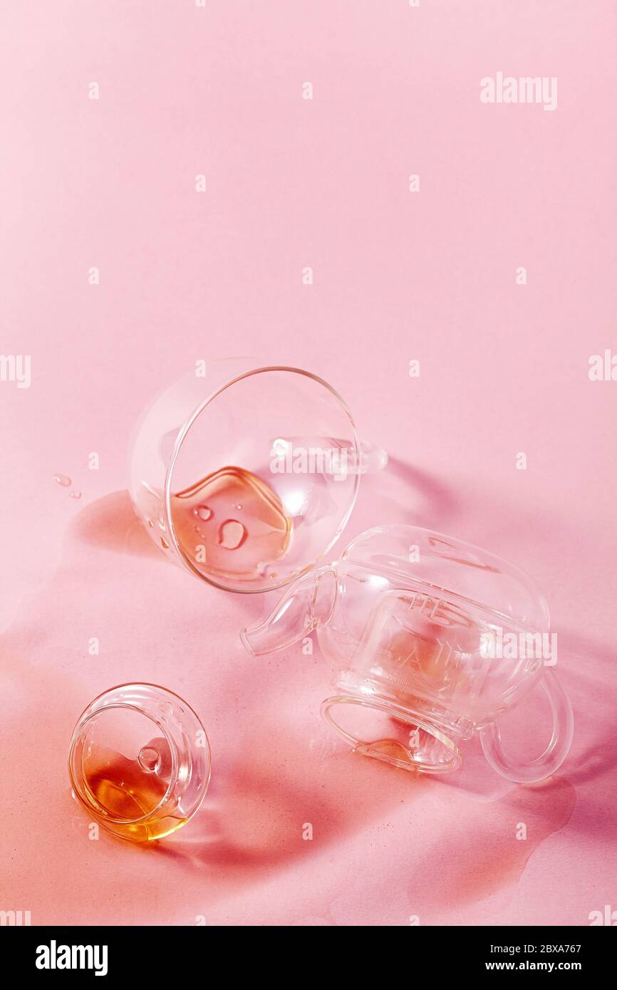jeté une théière en verre et du thé renversé sur fond rose. résumé Banque D'Images jeté une théière en verre et du thé renversé sur fond rose. résumé Banque D'Images