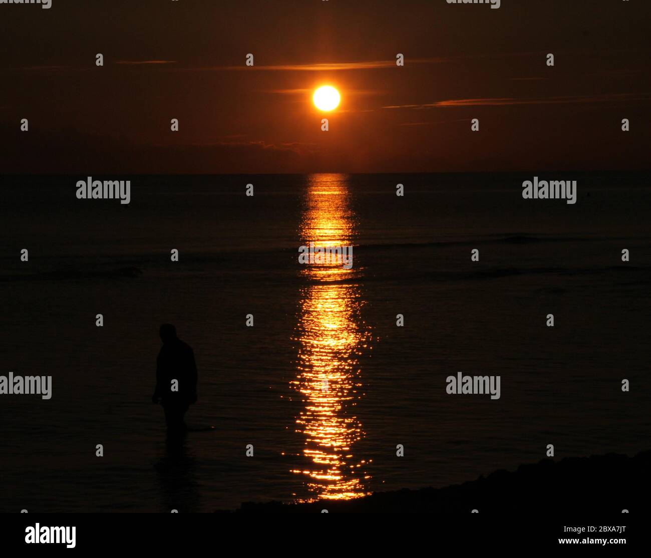 Le soleil se reflète sur une mer calme au coucher du soleil Banque D'Images