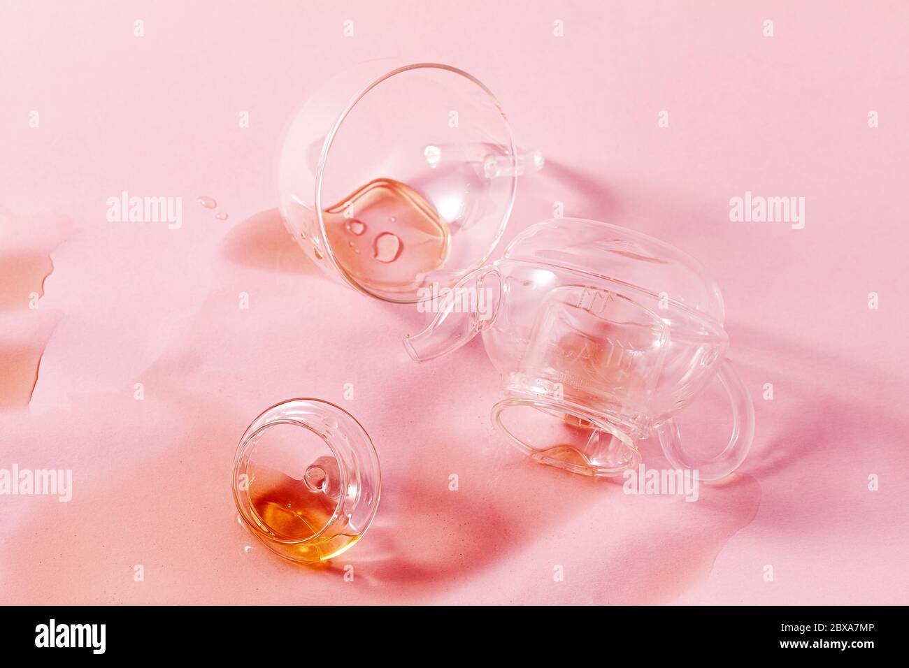 jeté une théière en verre et du thé renversé sur fond rose. résumé Banque D'Images jeté une théière en verre et du thé renversé sur fond rose. résumé Banque D'Images