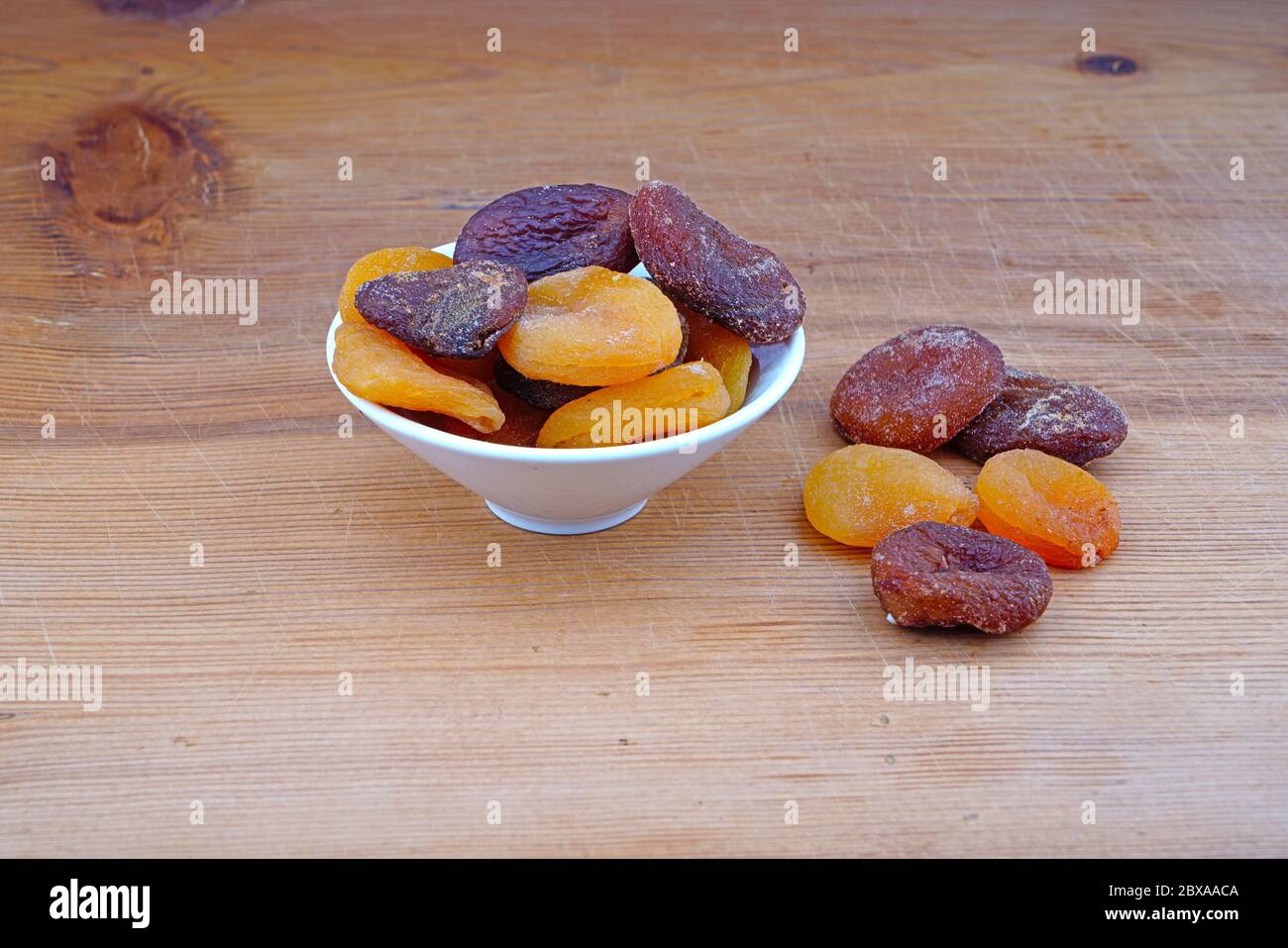Plateau d'abricots séchés biologiques et d'abricots séchés déversés sur fond de bois Banque D'Images