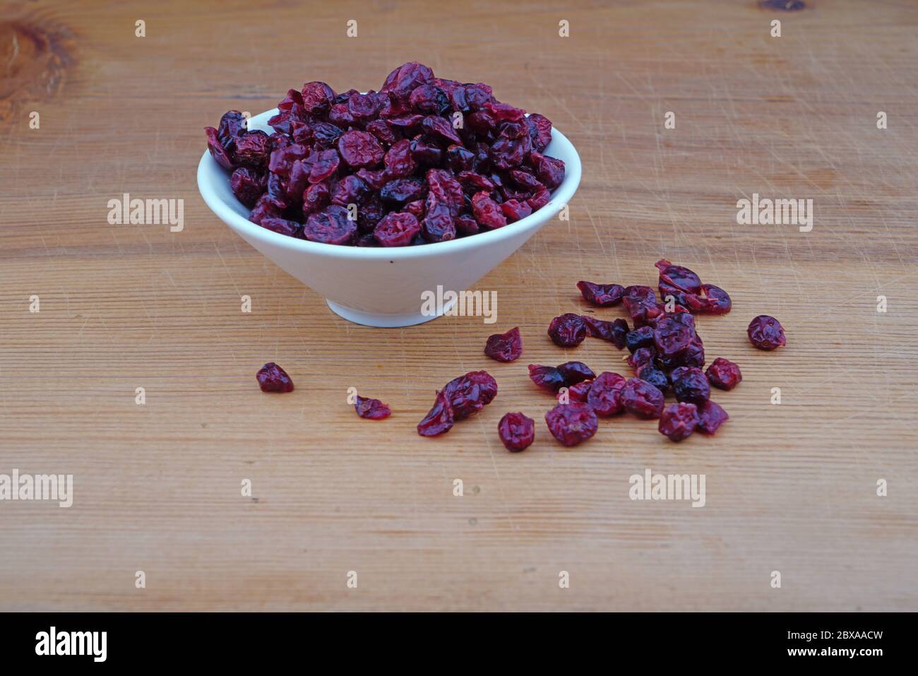 Plateau de cerises séchées biologiques et de cerises séchées déversées sur fond de bois Banque D'Images