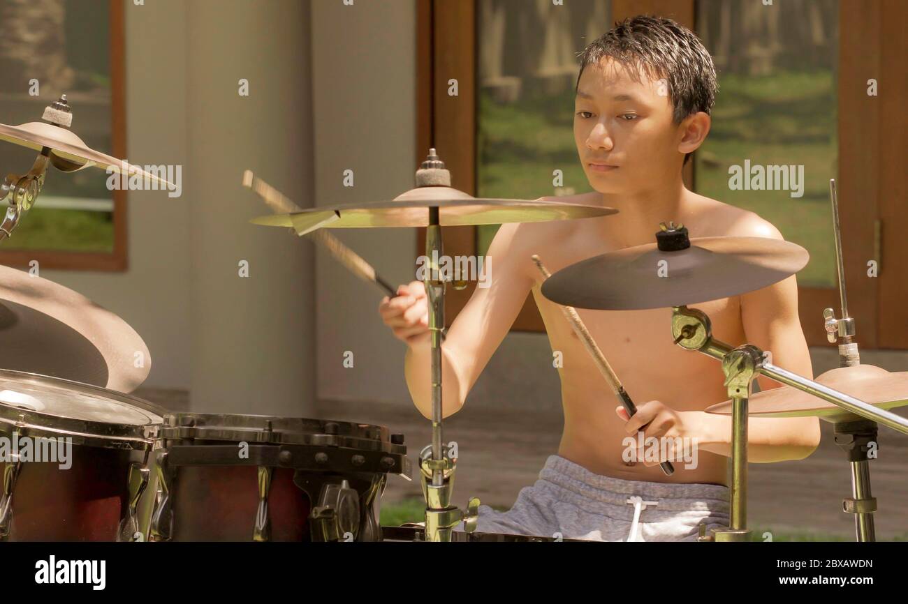 Adolescent asiatique américain jouant des dums. Portrait d'été d'un jeune  garçon charmant pratiquant sur le kit de batterie à la maison jardin  répétition de chant rock appréciant son ho Photo Stock -