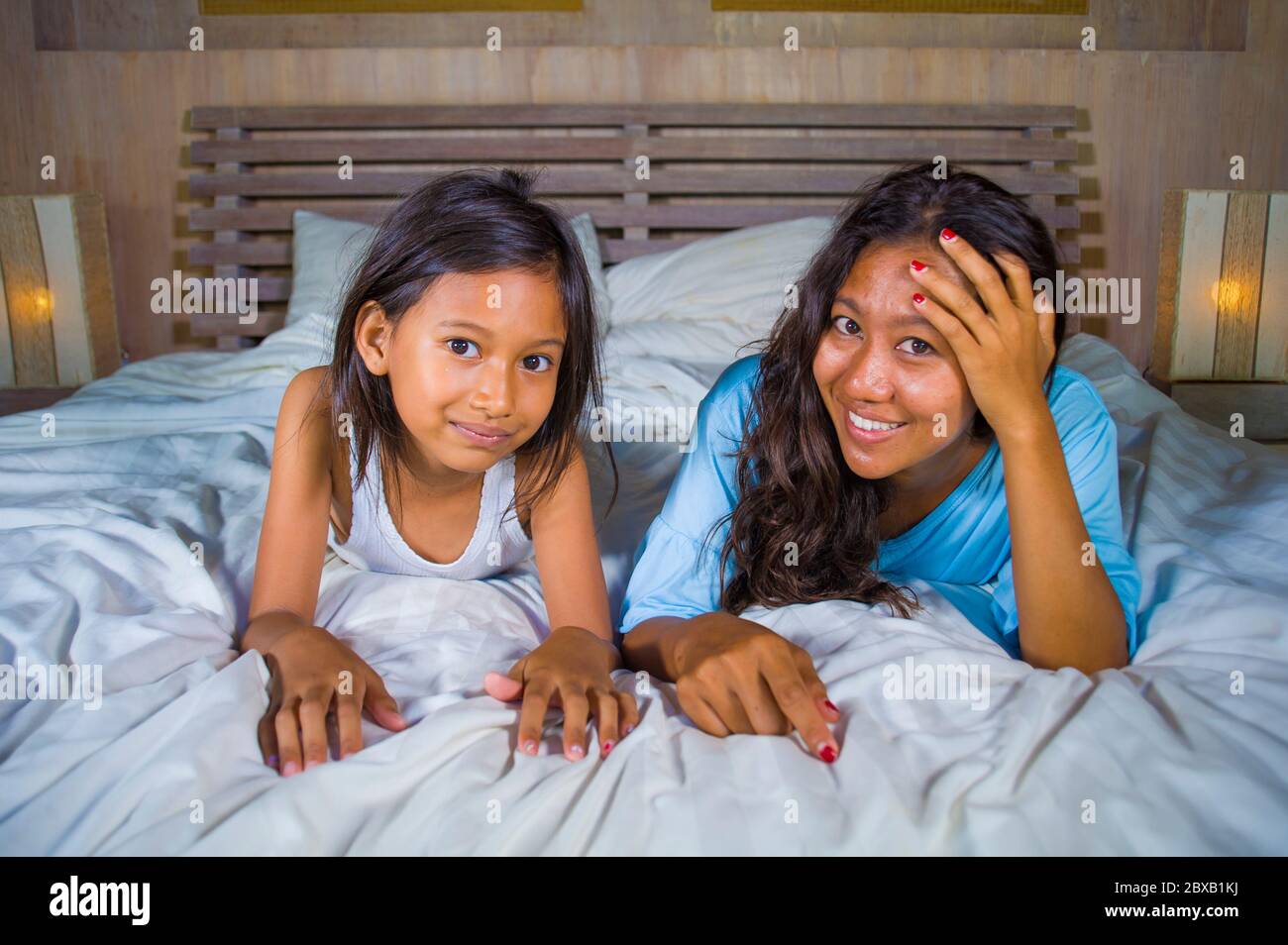 Portrait de la chambre de style de vie d'une femme asiatique heureuse à la maison posant avec sa belle fille de 8 ans dans le lit souriant ludique gai en mère et Banque D'Images