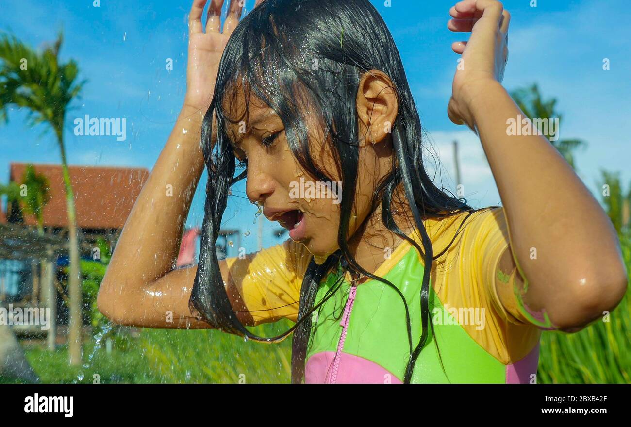 jeune heureux et insouciant beau enfant de 7 ou 8 ans plein air ayant la douche à une belle terrasse de riz ludique sous l'eau portant une jolie fille Banque D'Images