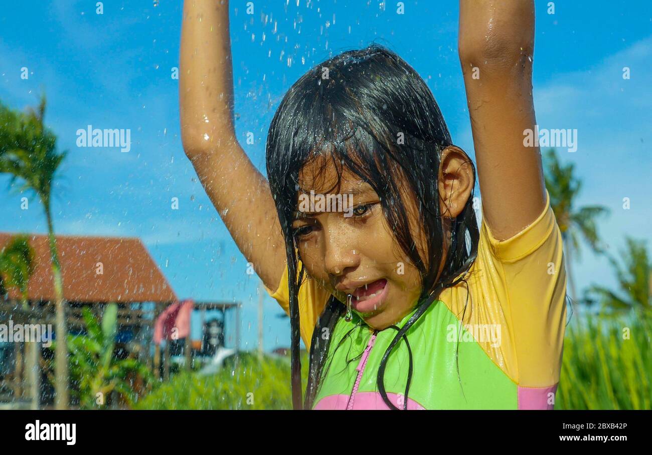 jeune heureux et insouciant beau enfant de 7 ou 8 ans plein air ayant la douche à une belle terrasse de riz ludique sous l'eau portant une jolie fille Banque D'Images