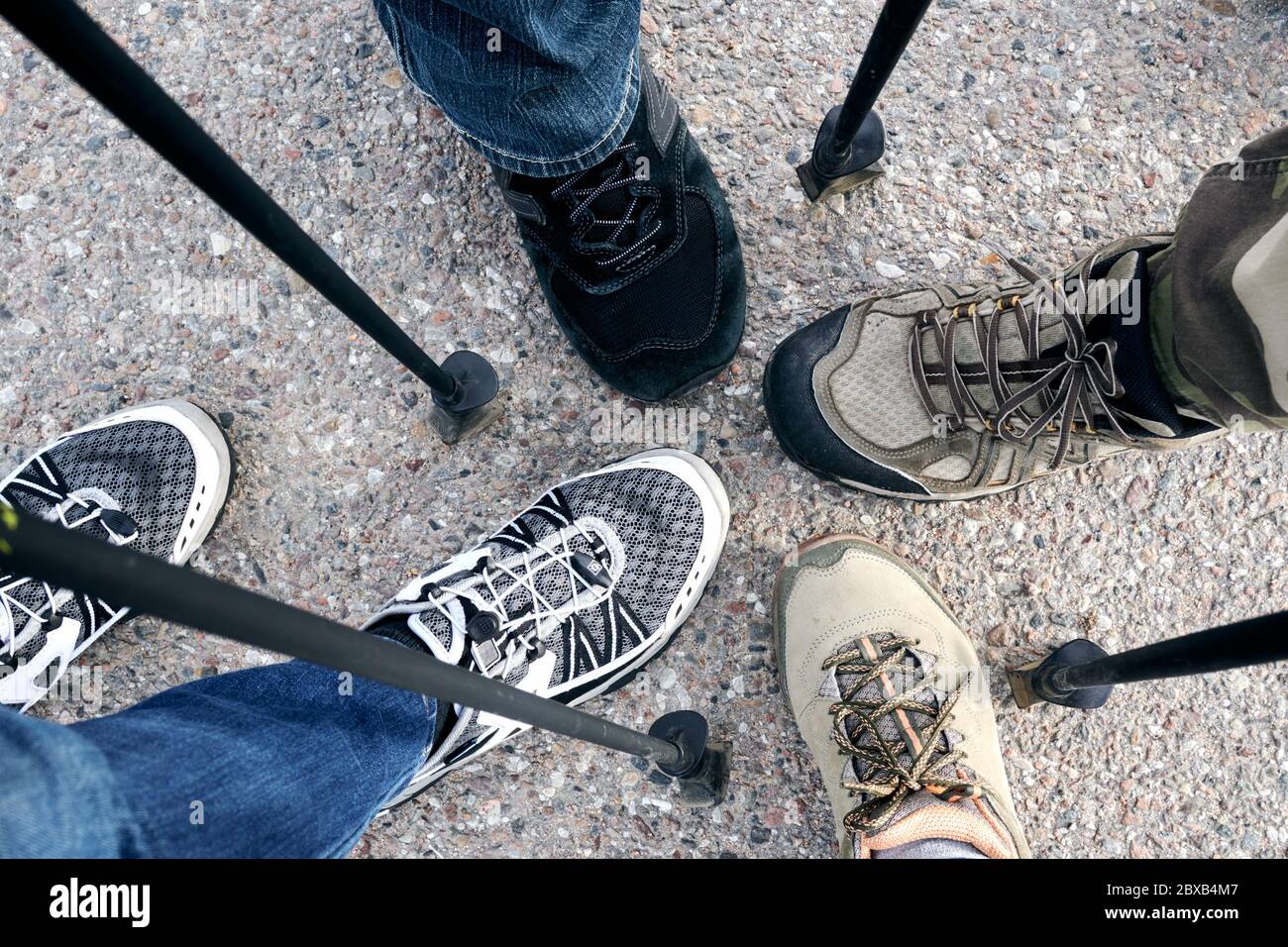 Concept de marche nordique en extérieur. Hommes, femmes pieds jambes dans les chaussures de randonnée se tiennent sur le chemin d'asphalte. Vue de dessus. Banque D'Images