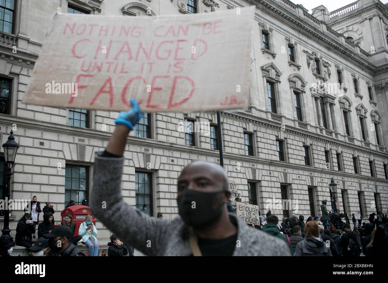 Un manifestant passe devant les bâtiments institutionnels du centre de Londres et tient une pancarte contre le racisme systémique au Royaume-Uni. Banque D'Images