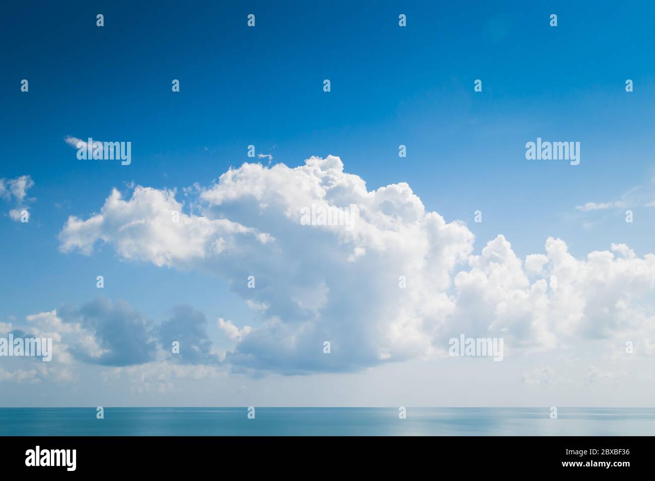 Nuages blancs moelleux et mer turquoise sur ciel bleu Banque D'Images