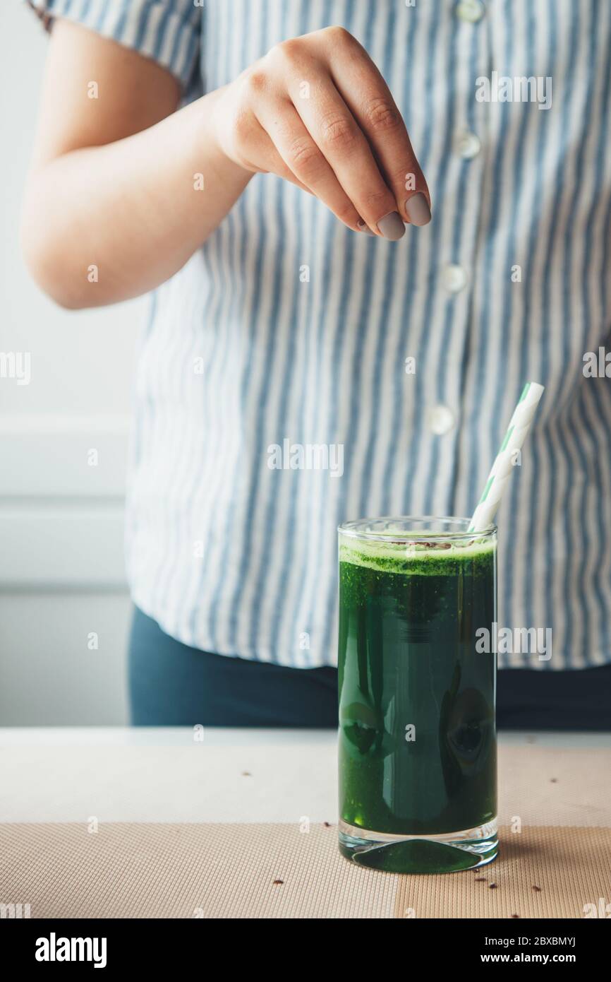 Une jeune femme qui a des habitudes saines prépare un jus de légumes au sésame Banque D'Images