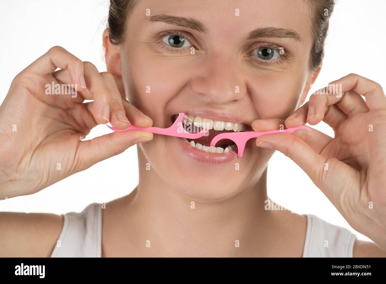 Hygiène de la cavité buccale. Une jeune fille nettoie les dents avec de la soie dentaire, souriant et montrant un signe correct sur fond blanc. Banque D'Images