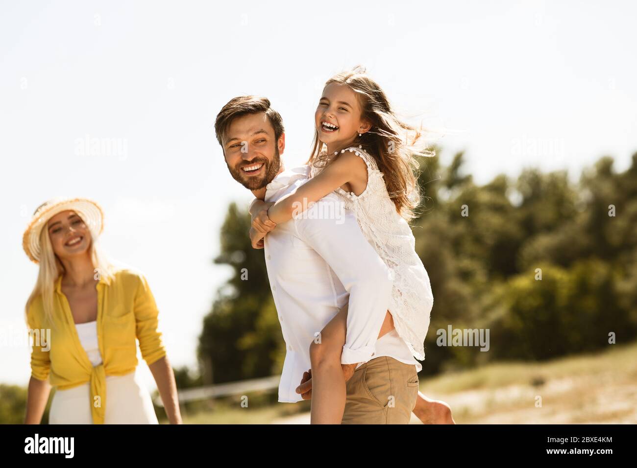 Bonne famille en train de profiter de la journée d'été ensemble, Père transportant sa fille à l'extérieur Banque D'Images