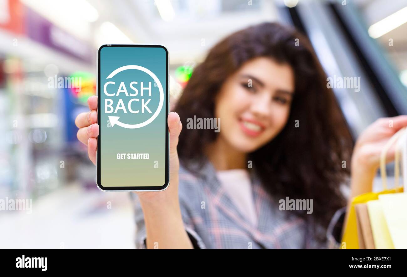 Jeune femme tenant un smartphone avec l'application Cashback ouverte à l'écran Banque D'Images