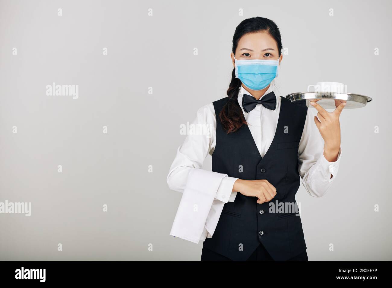 Portrait de la serveuse asiatique de restaurant dans le masque médical servant la nourriture Banque D'Images