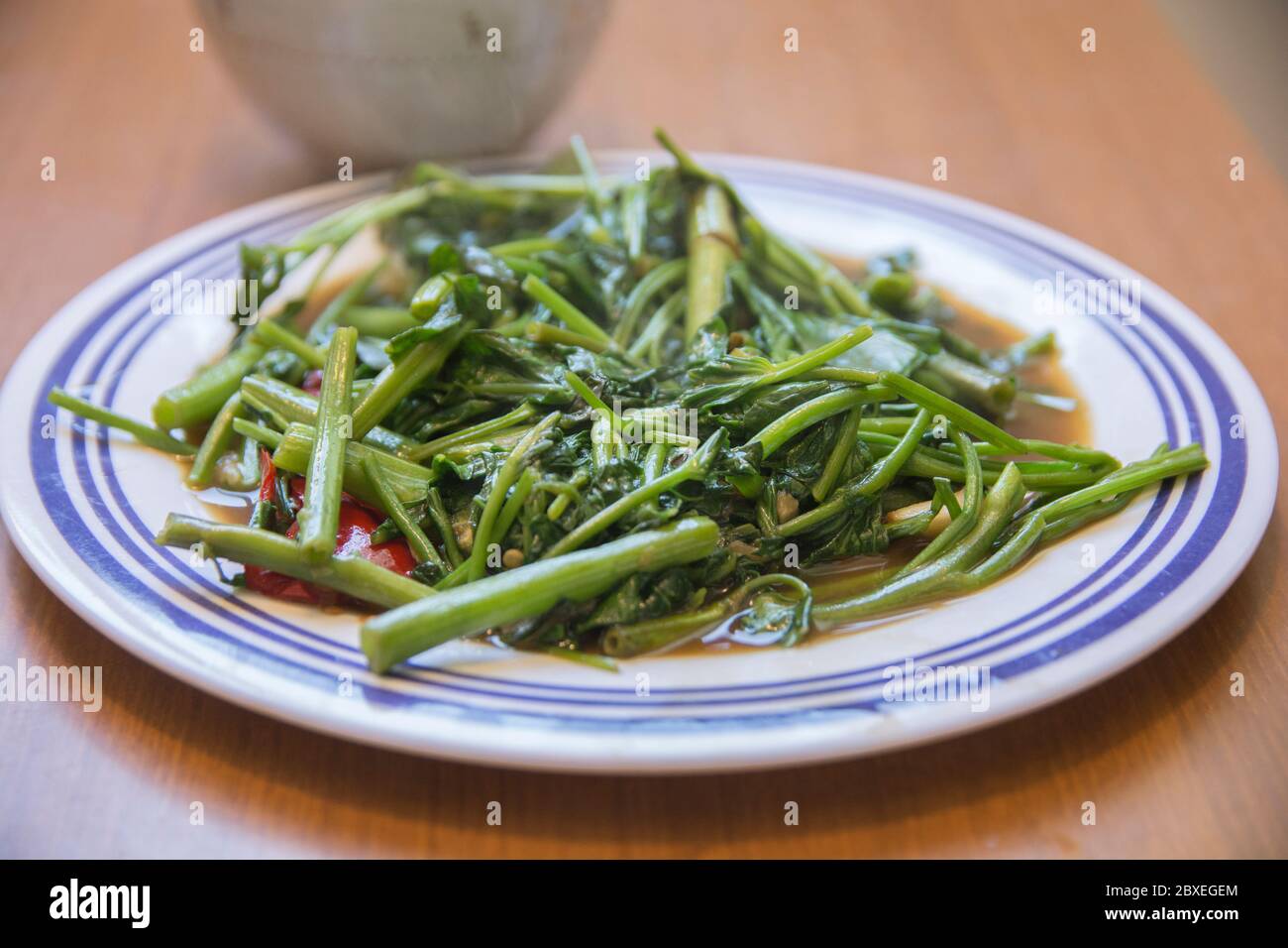 Vue de dessus de 'Pad Pak Boong', un plat traditionnel thaïlandais : légumes 'Morning Glory' sautés (Ipomoea aquatica) servis dans une assiette blanche Banque D'Images