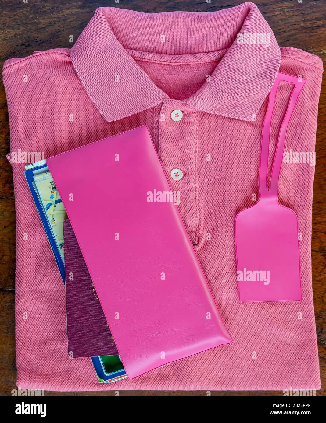 Composition rose totale de polo et documents de voyage avec étiquette à bagages sur table en bois Banque D'Images