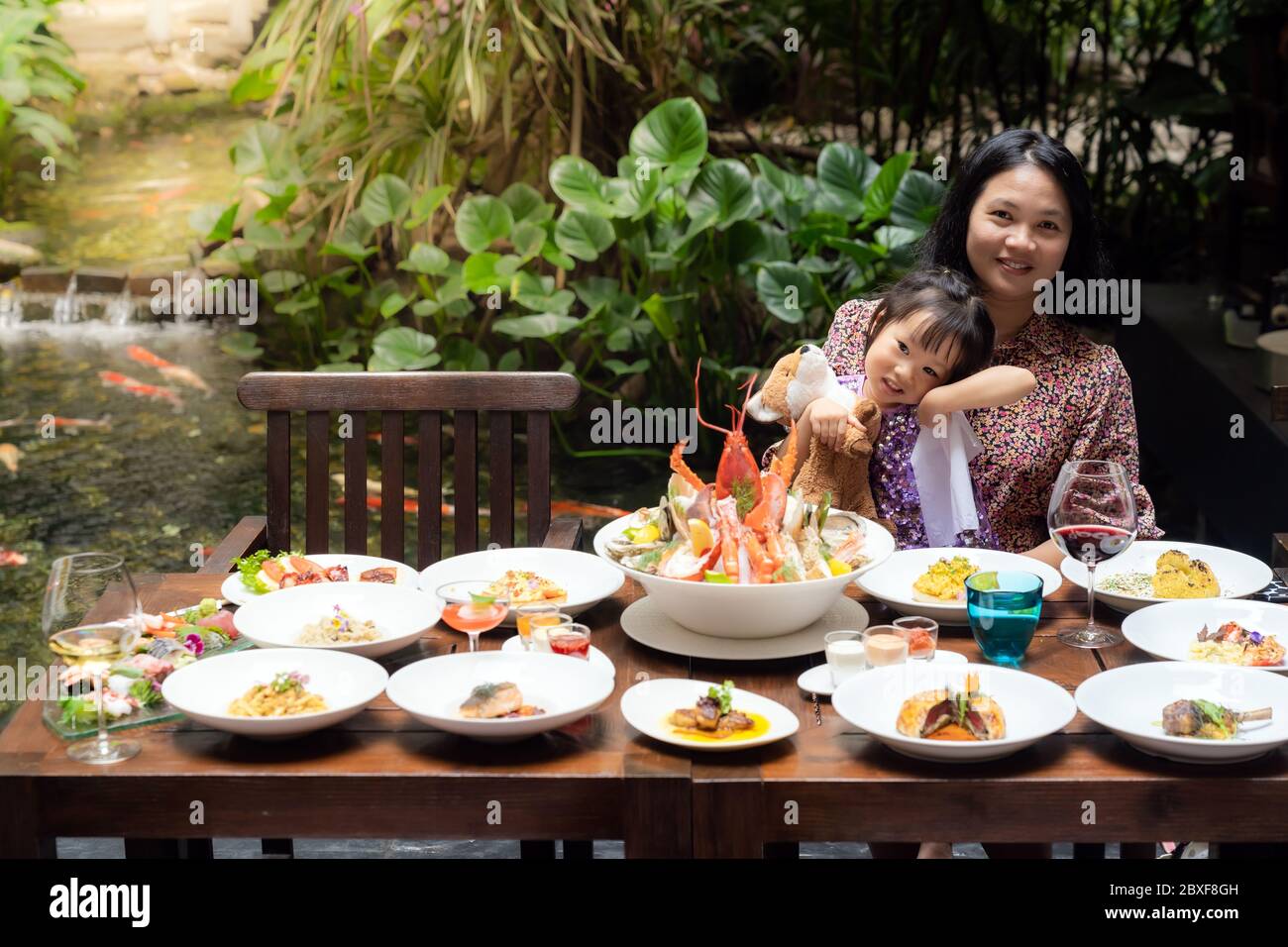 Portrait de maman et fille au jardin du restaurant de homard crevettes steak bœuf pâtes d'agneau spaghetti risotto riz sushi sashimi et vin à l'aide de FO Banque D'Images