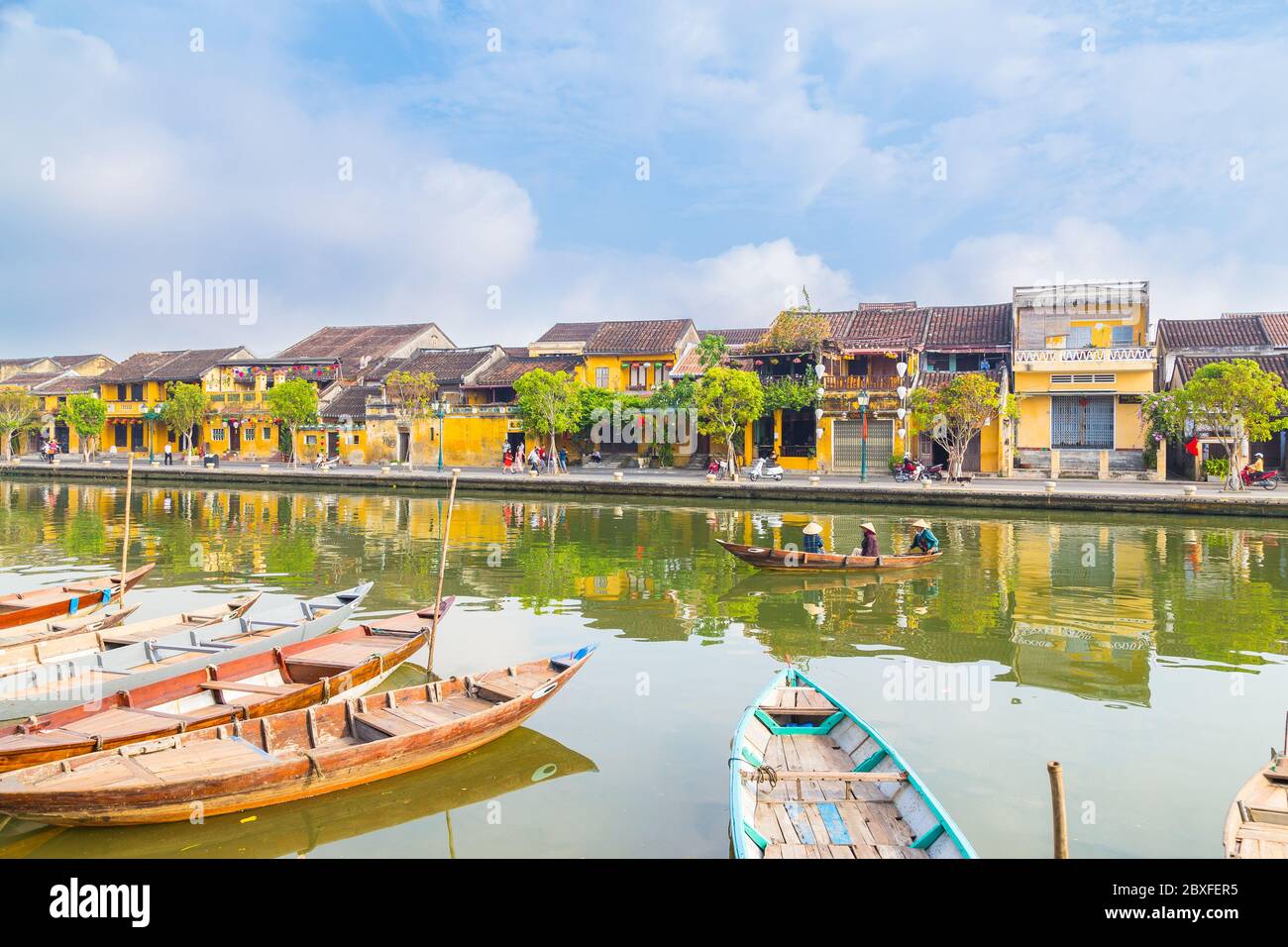 HOI AN, VIETNAM - 25 MARS 2017 : une vue sur l'ancien Hoi an de l'autre côté de la rivière Thu bon le matin. Bâtiments, bateaux, réflexions et lo Banque D'Images