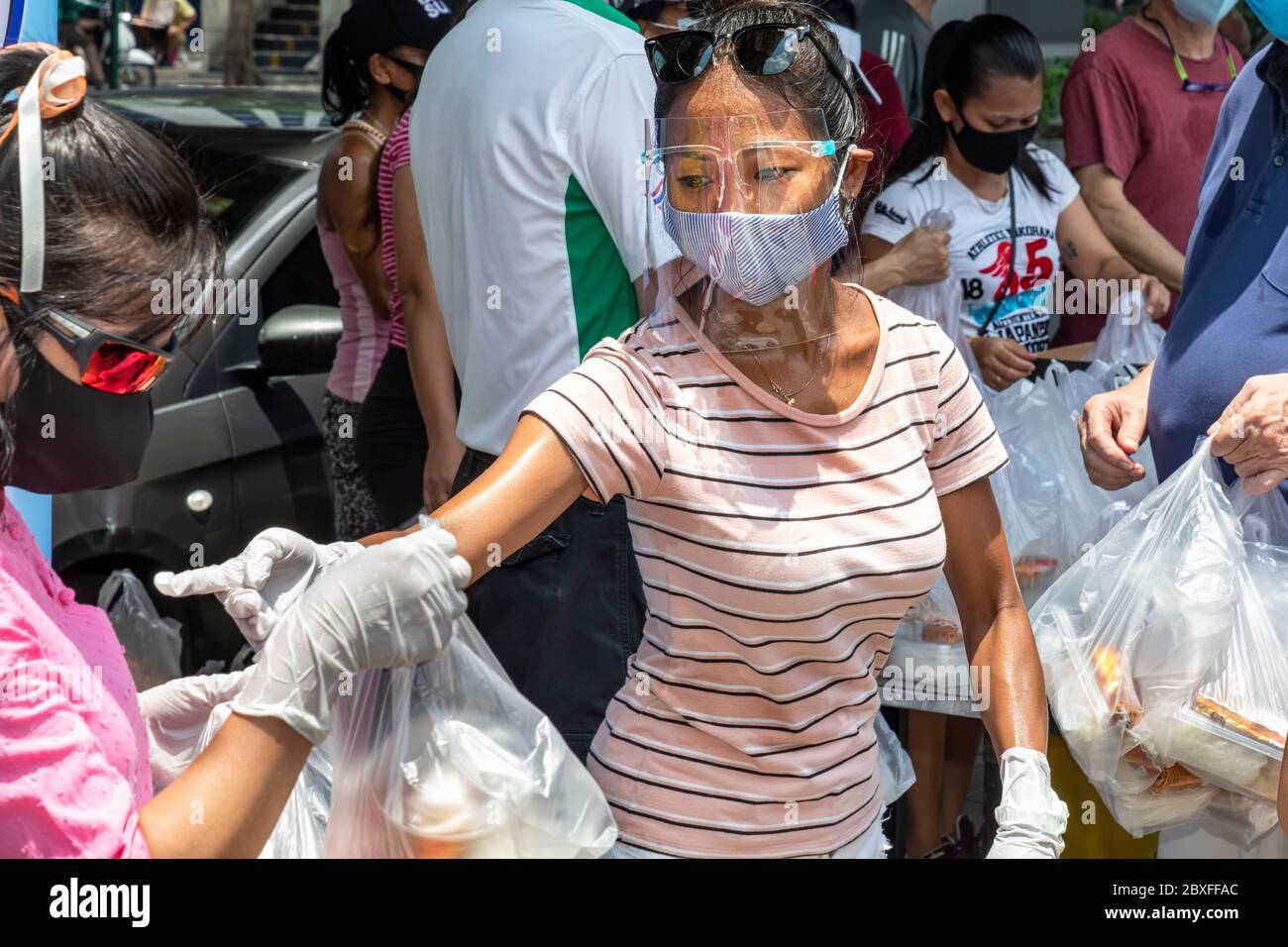 Faites du bénévolat avec un masque facial et des gants en donnant de la nourriture gratuite à la banque alimentaire pendant la pandémie de Covid, Bangkok, Thaïlande Banque D'Images