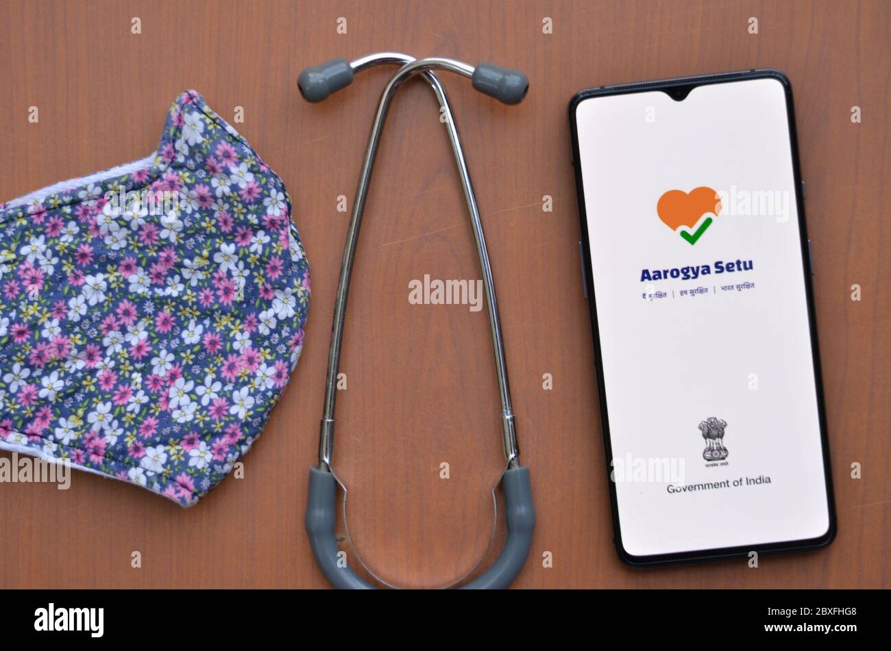 New Delhi, Inde, 2020. Flat Lay avec mobile montrant l'application Aarogya Setu avec stéthoscope et masque floral de designer fond en bois. Concept protec Banque D'Images
