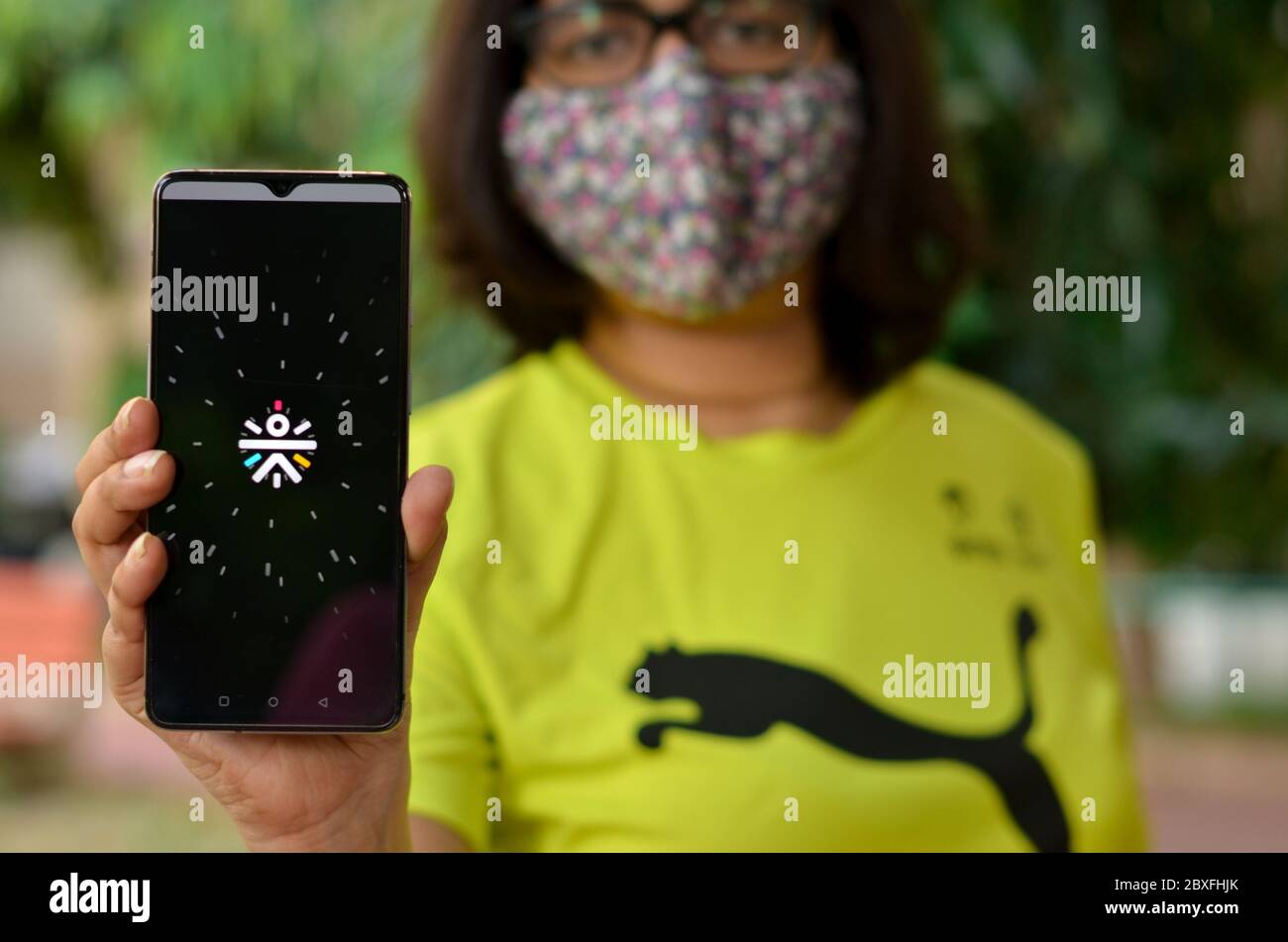 Mumbai, Inde, 2020. Fille portant un masque tenant un téléphone portable avec l'application Cure FIT. C'est une société de santé et de fitness qui offre une expérience numérique et hors ligne Banque D'Images
