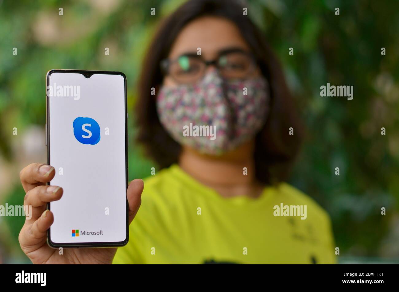 New York, États-Unis, 2020. Fille portant un masque montrer l'application Skype sur mobile en quarantaine à domicile pour la pandémie de la maladie de Corona virus (Covid-19).Skype est devenu un mois Banque D'Images