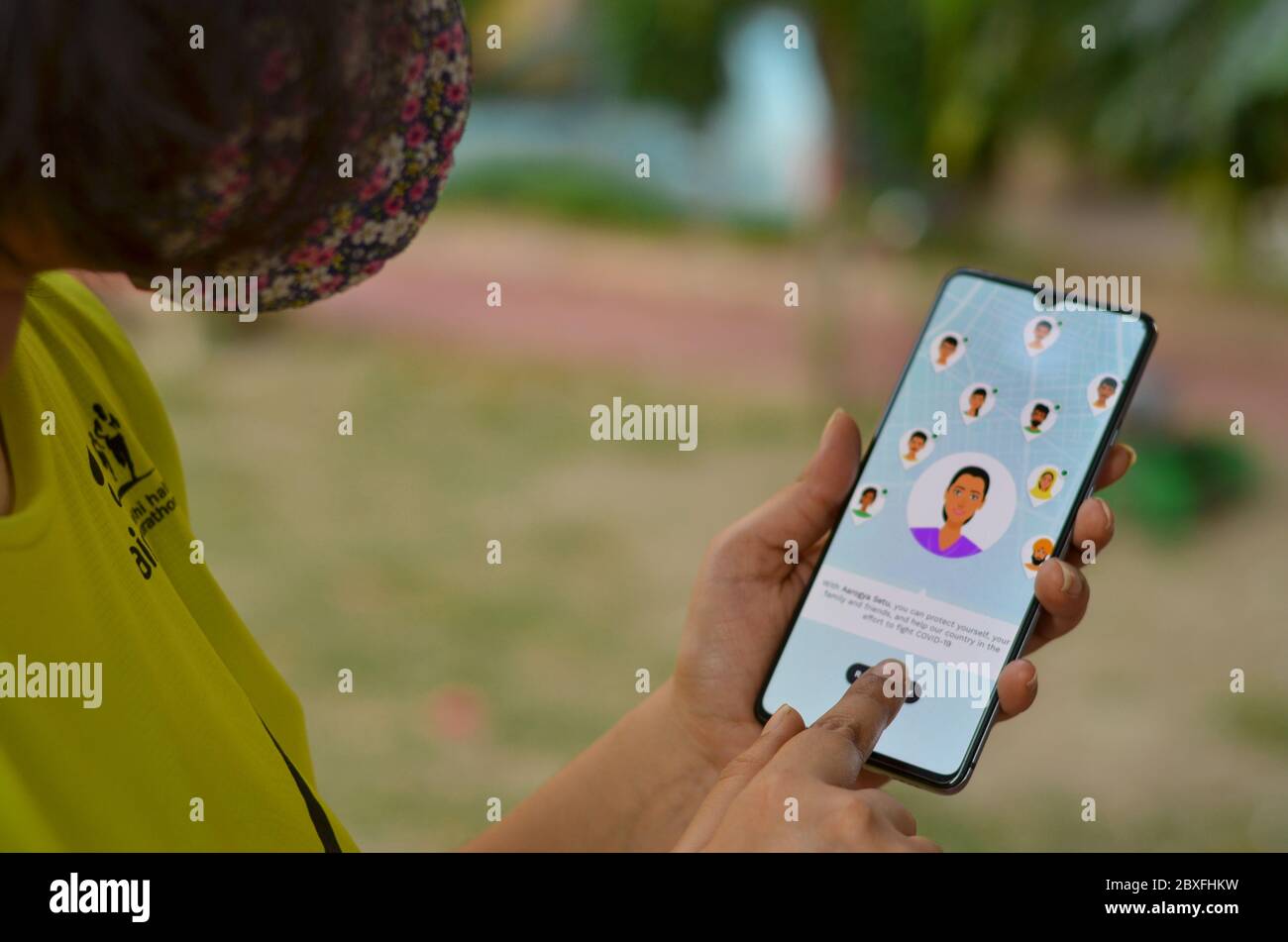 Delhi, Inde, 2020. Fille portant un masque installer l'application Aarogya Setu sur un téléphone portable en quarantaine à domicile. Il est lancé par le gouvernement indien pour la prévention et la Banque D'Images