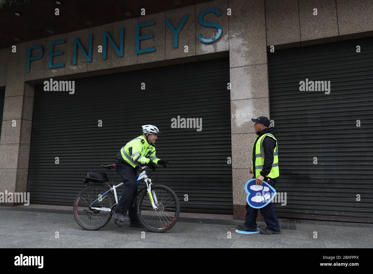 Le sergent Garda Rodger Quinn (à gauche) s'adresse à Joe Carroll, un employé du conseil municipal de Dublin, qui a mis des autocollants de file d'attente sur O'Connell Street, à l'extérieur de Penneys à Dublin, avant sa réouverture alors que la phase 2 de la carte routière de récupération du coronavirus irlandais commencera lundi comme prévu, avec d'autres mesures initialement prévues pour les phases ultérieures. Banque D'Images