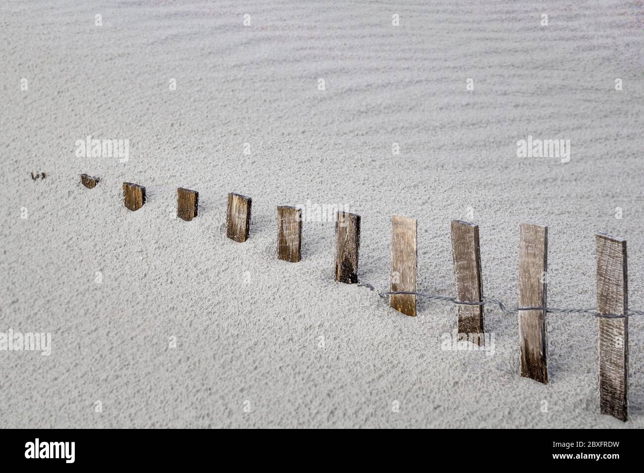 la clôture de tempête disparaît dans la dune de sable de plage qui dérive Banque D'Images
