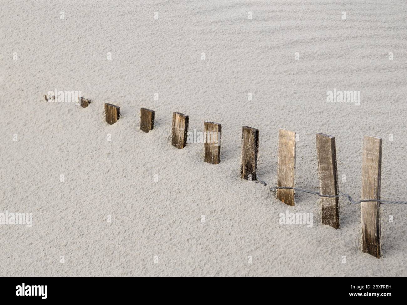 la clôture de tempête disparaît dans la dune de sable de plage qui dérive Banque D'Images