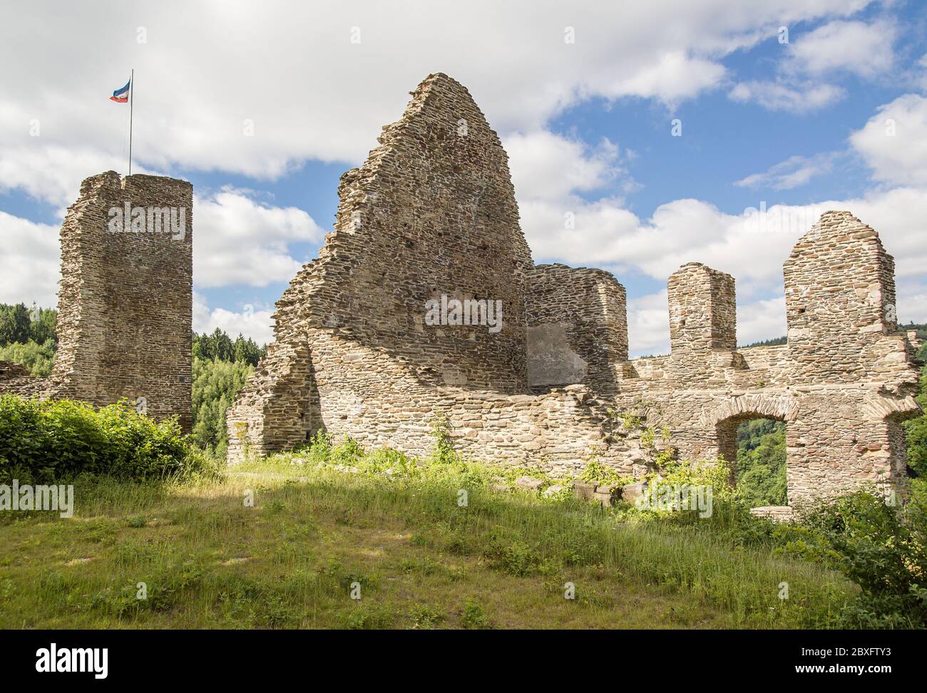Les ruines d'un château médiéval, illuminé par le soleil, un jour d'été légèrement nuageux. Drapeaux en haut. Banque D'Images