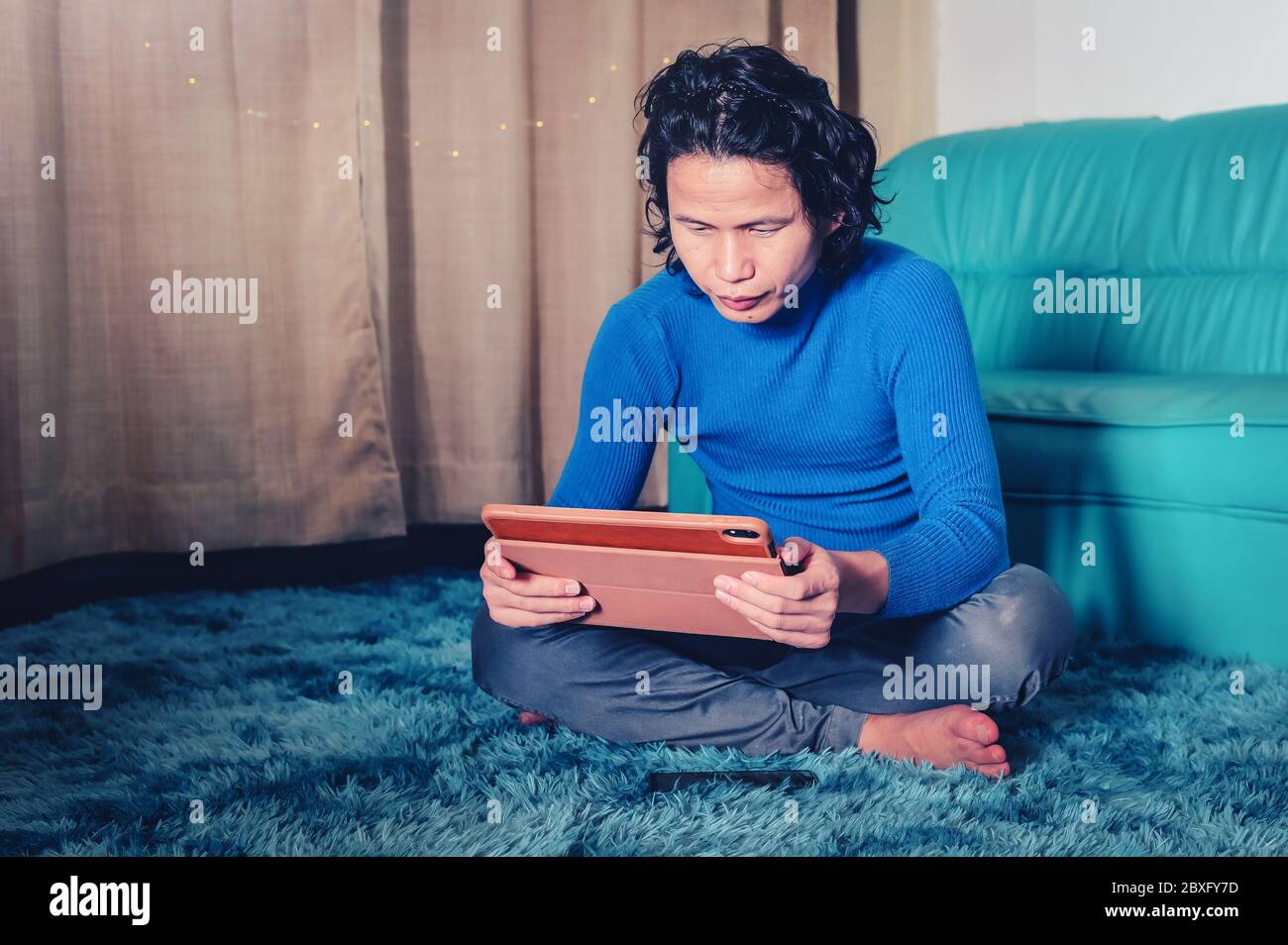 Homme d'affaires lisant des informations ou vérifier les médias sociaux dans une tablette numérique, en posant un tapis dans le salon de la maison avec sofain nuit séjour à la maison Banque D'Images