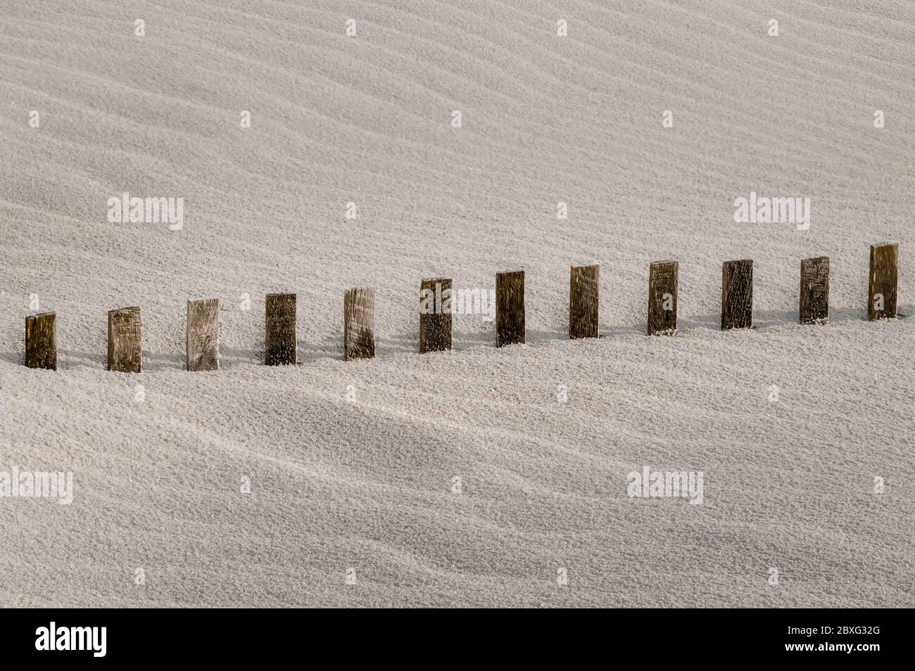 la clôture de tempête disparaît dans la dune de sable de plage qui dérive Banque D'Images